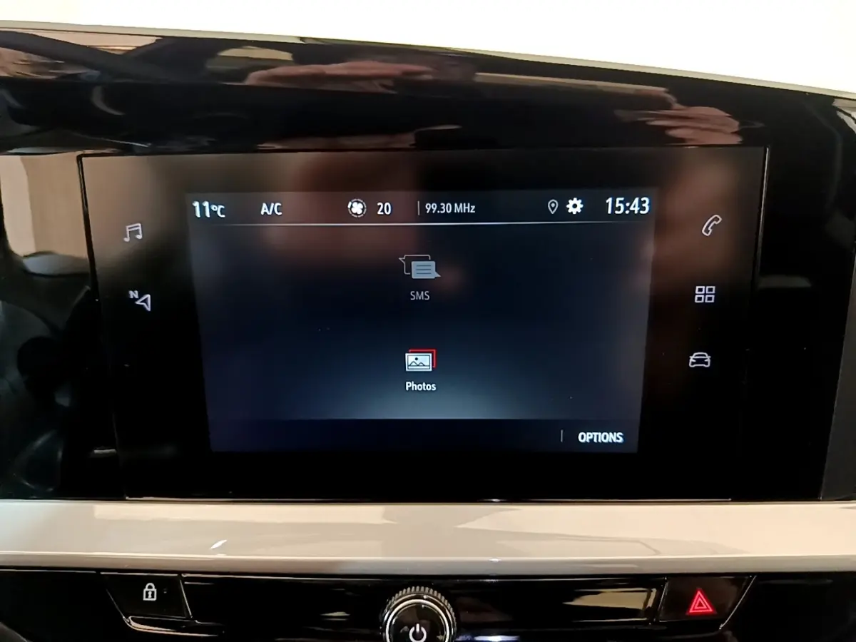 Écran tactile central de l’Opel Mokka 2024 affichant les options SMS et photos, avec commandes tactiles latérales visibles.