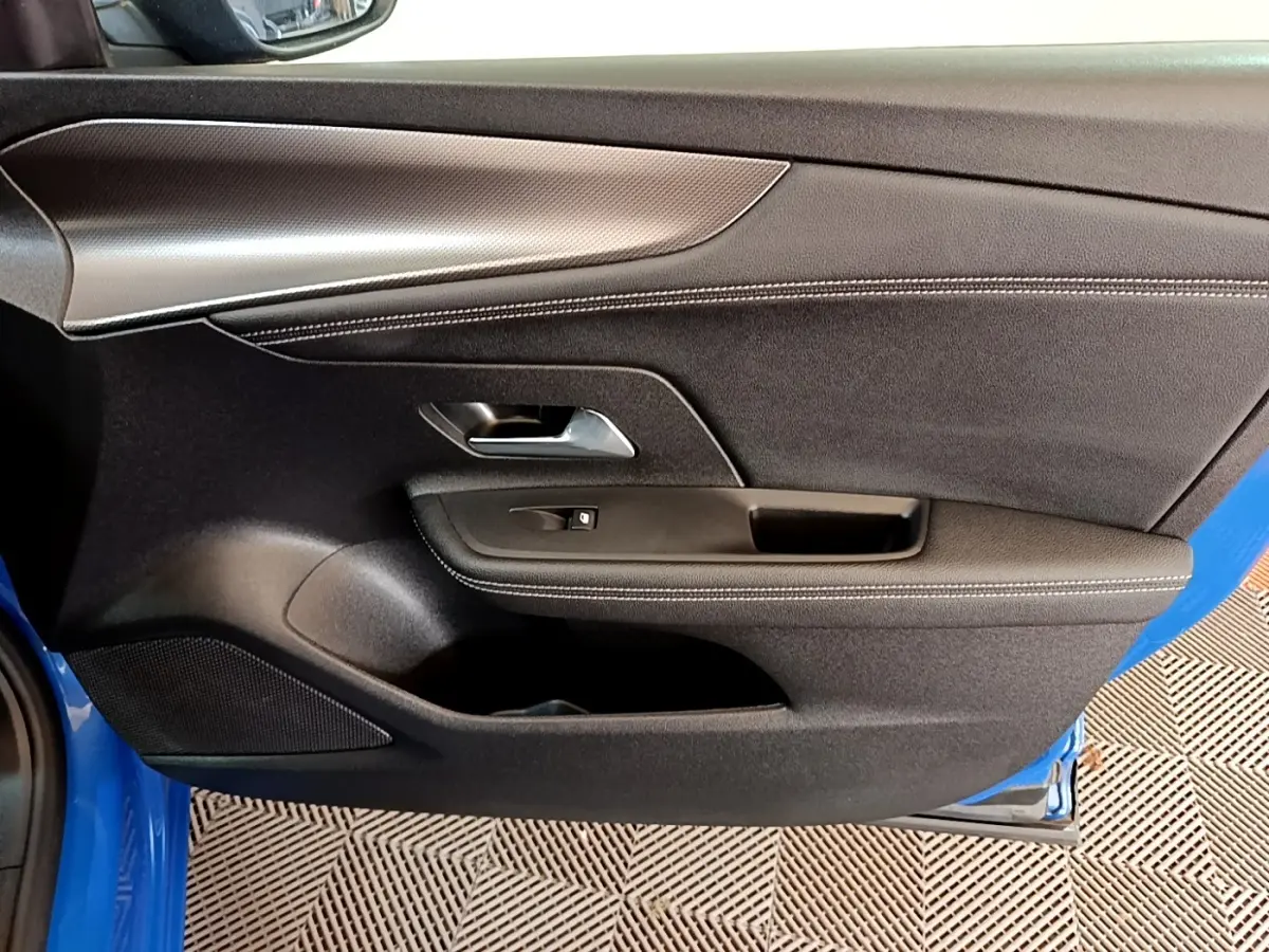 Vue rapprochée de la porte avant gauche de l’Opel Mokka bleu 2024 avec garniture noire et poignée argentée.