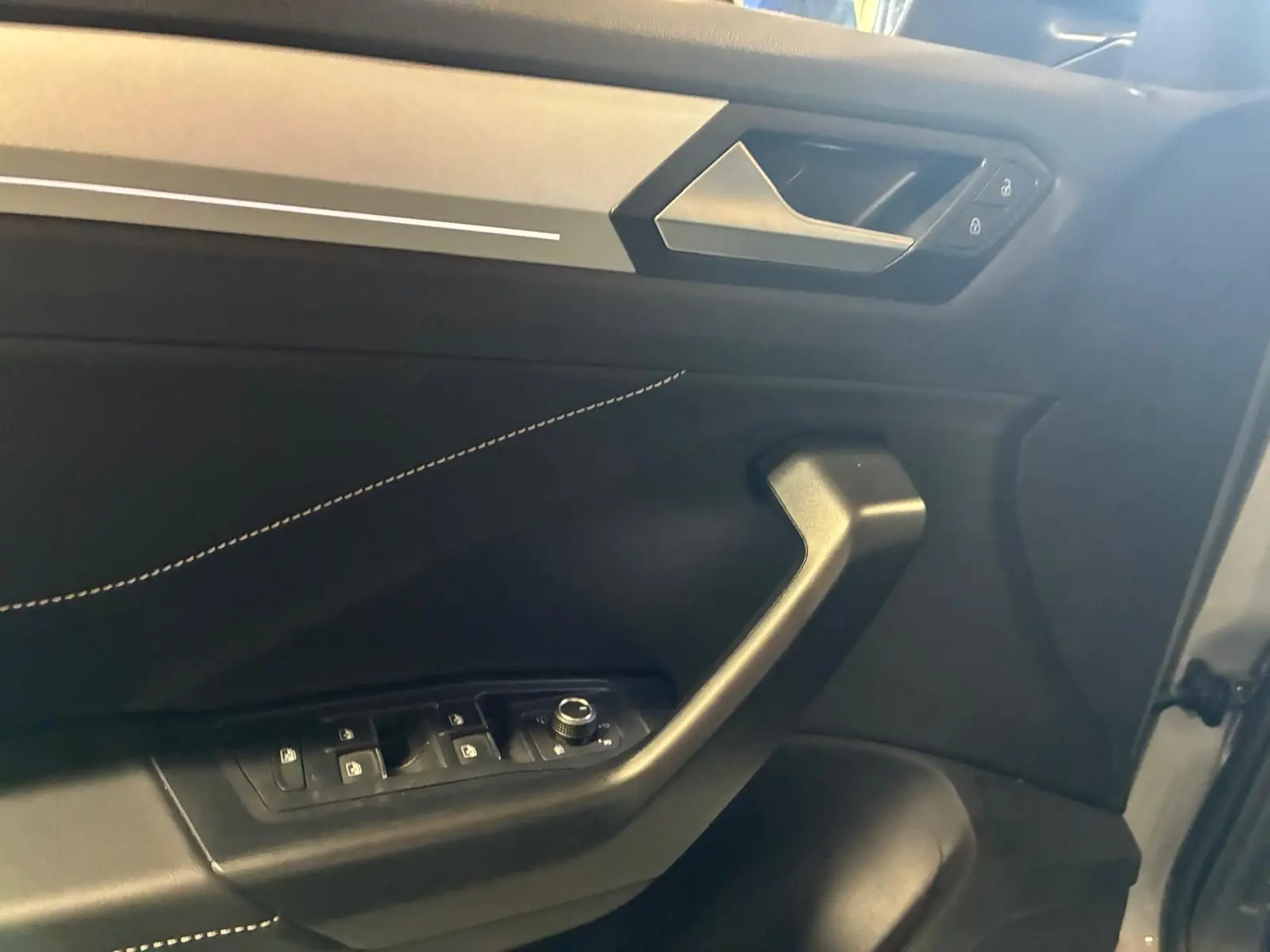 Intérieur côté gauche de la porte avant du Volkswagen T-Roc gris clair, avec commandes de vitres et serrure visibles.