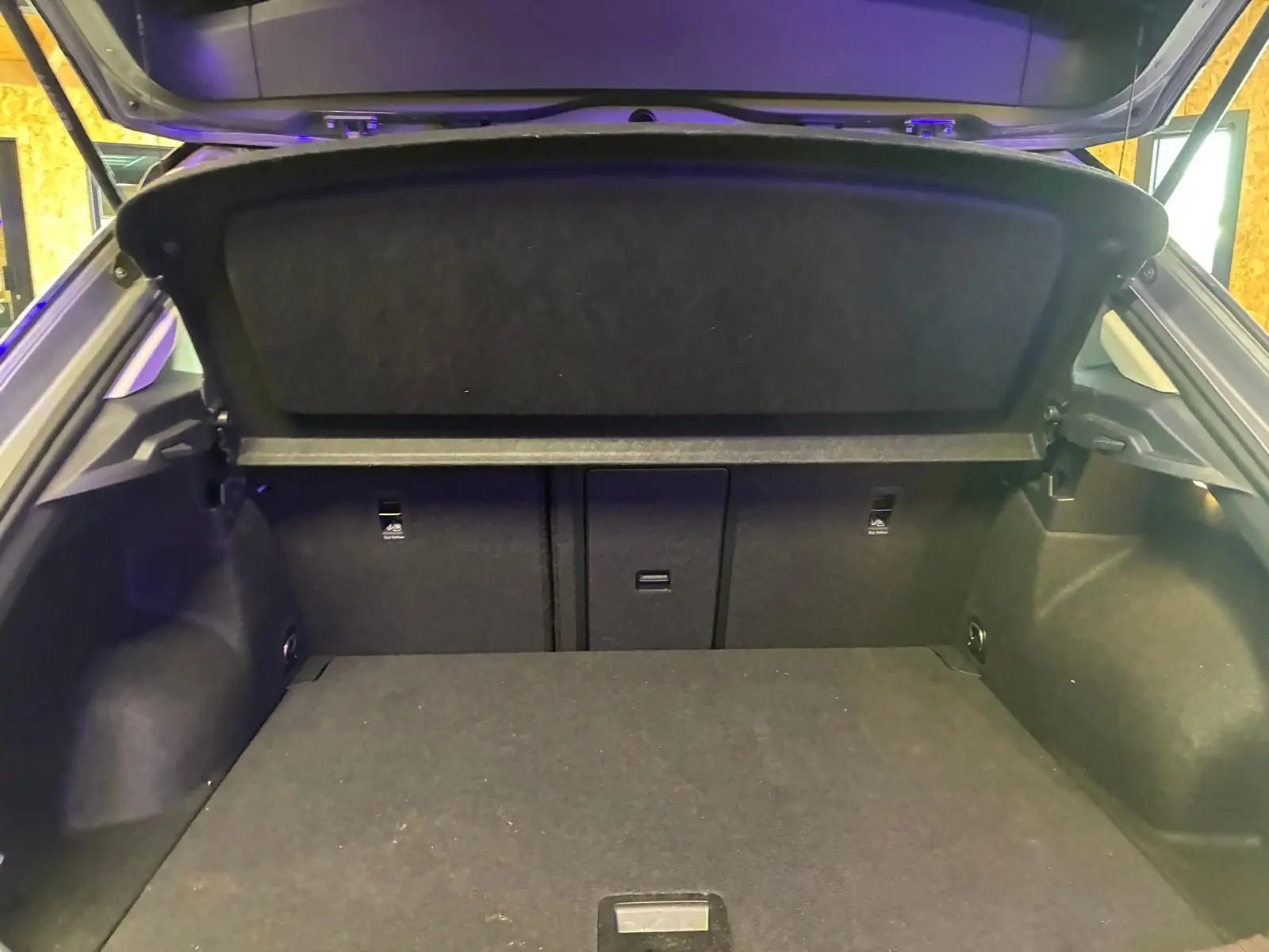 Coffre ouvert vu de l'arrière d'un Volkswagen T-Roc gris clair 2025, montrant l'espace de chargement et la plage arrière.