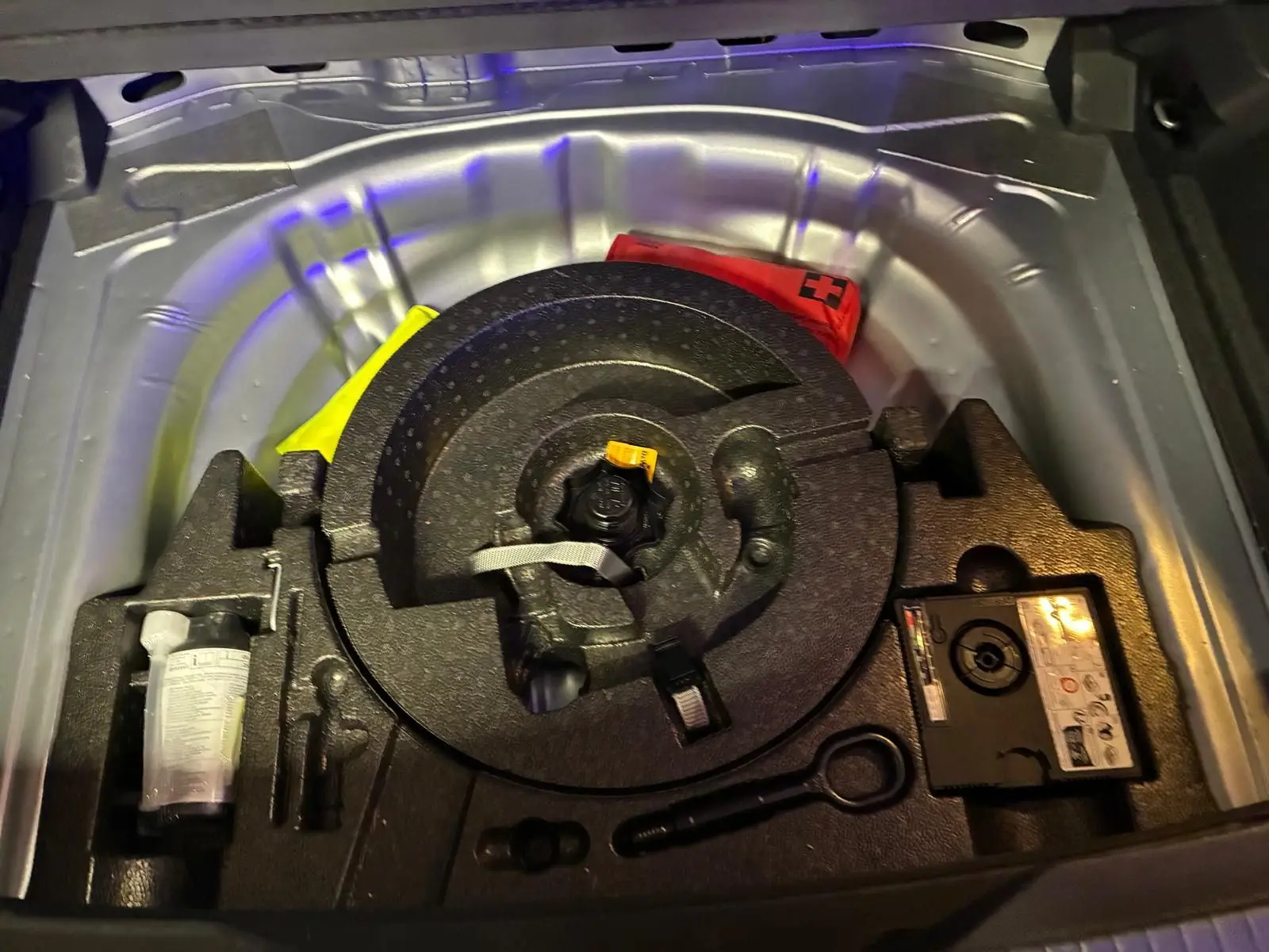 Coffre ouvert montrant la roue de secours et les outils de bord du Volkswagen T-Roc gris clair, version 2025.