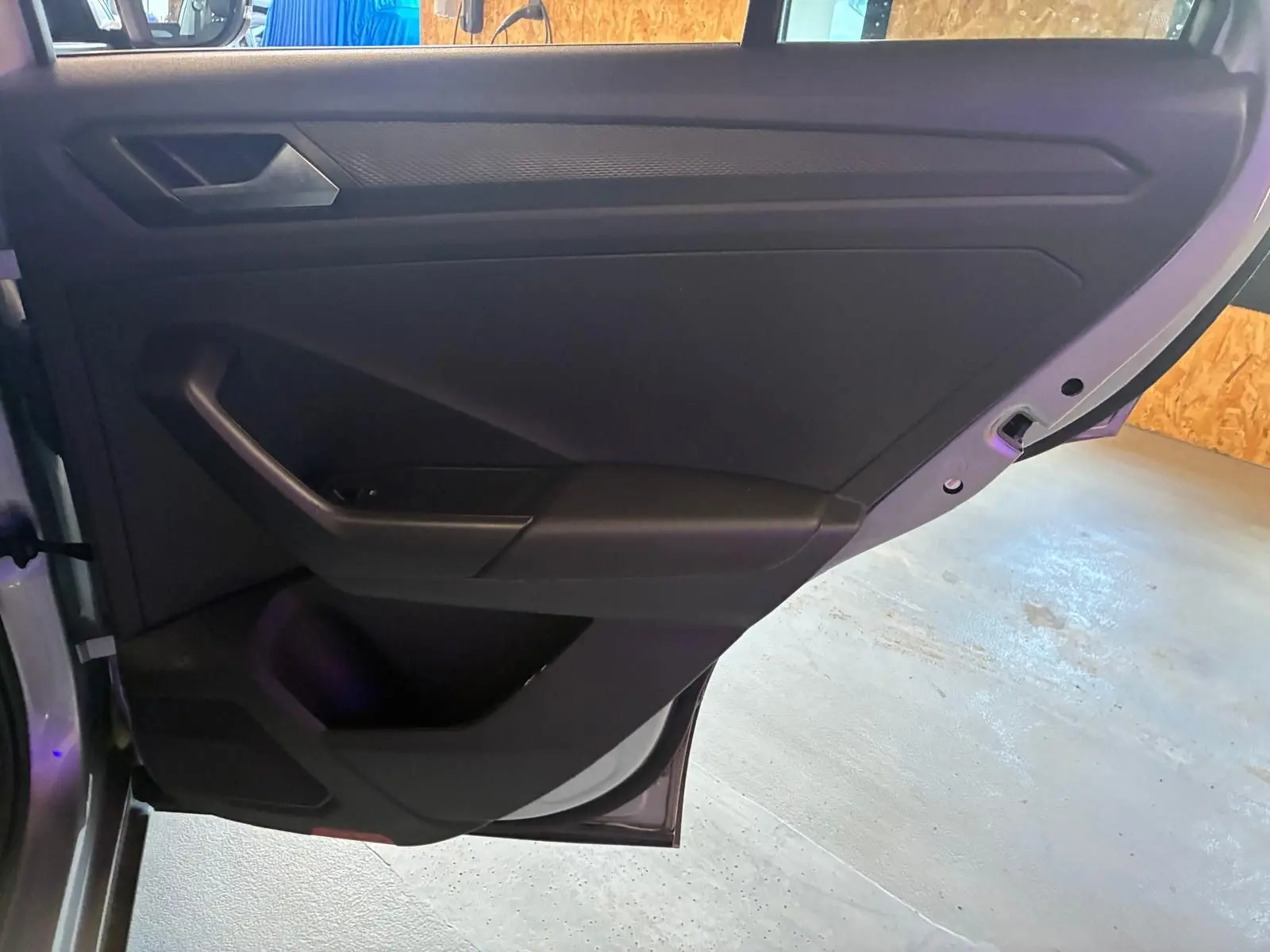Vue rapprochée de la porte arrière droite du Volkswagen T-Roc gris clair, montrant les commandes et le rangement intérieur.