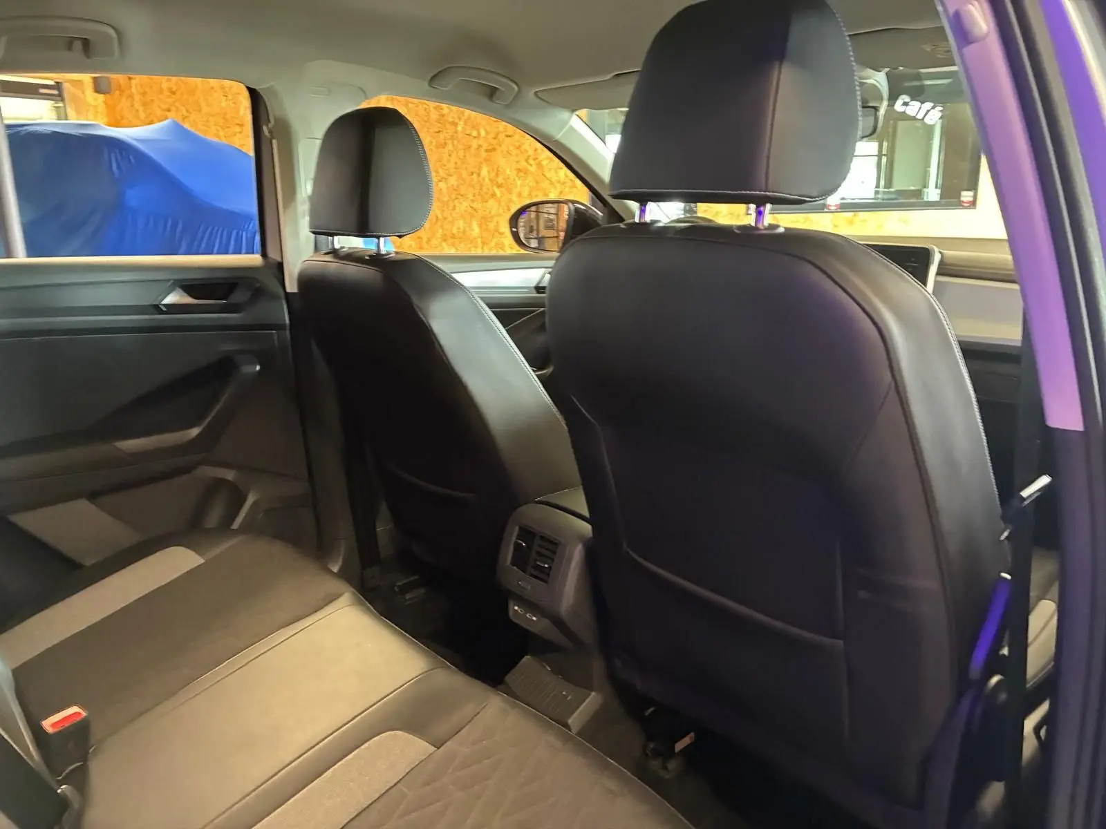 Vue intérieure arrière du Volkswagen T-Roc gris clair 2025, sièges en tissu noir avec détails gris et aérateurs centraux.