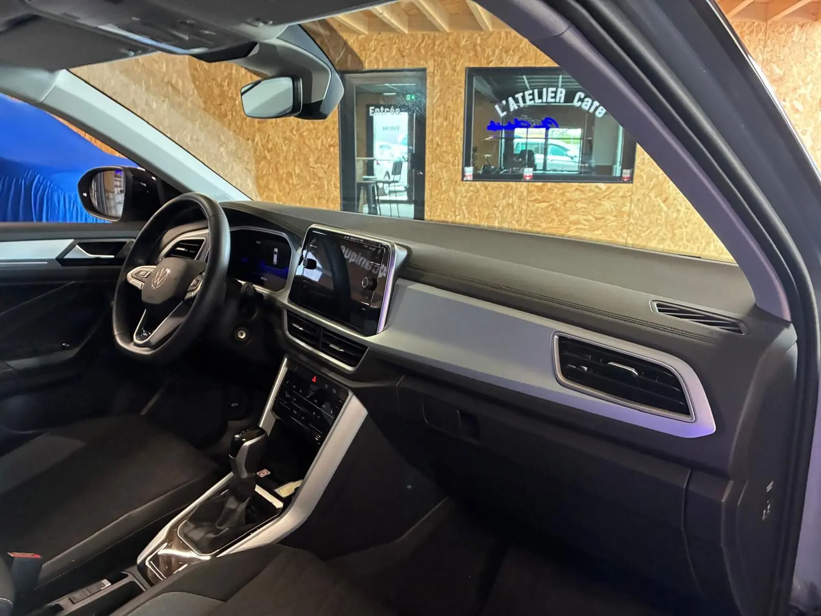 Vue intérieure côté conducteur du Volkswagen T-Roc 2025, mettant en valeur le tableau de bord moderne et l’écran tactile central.