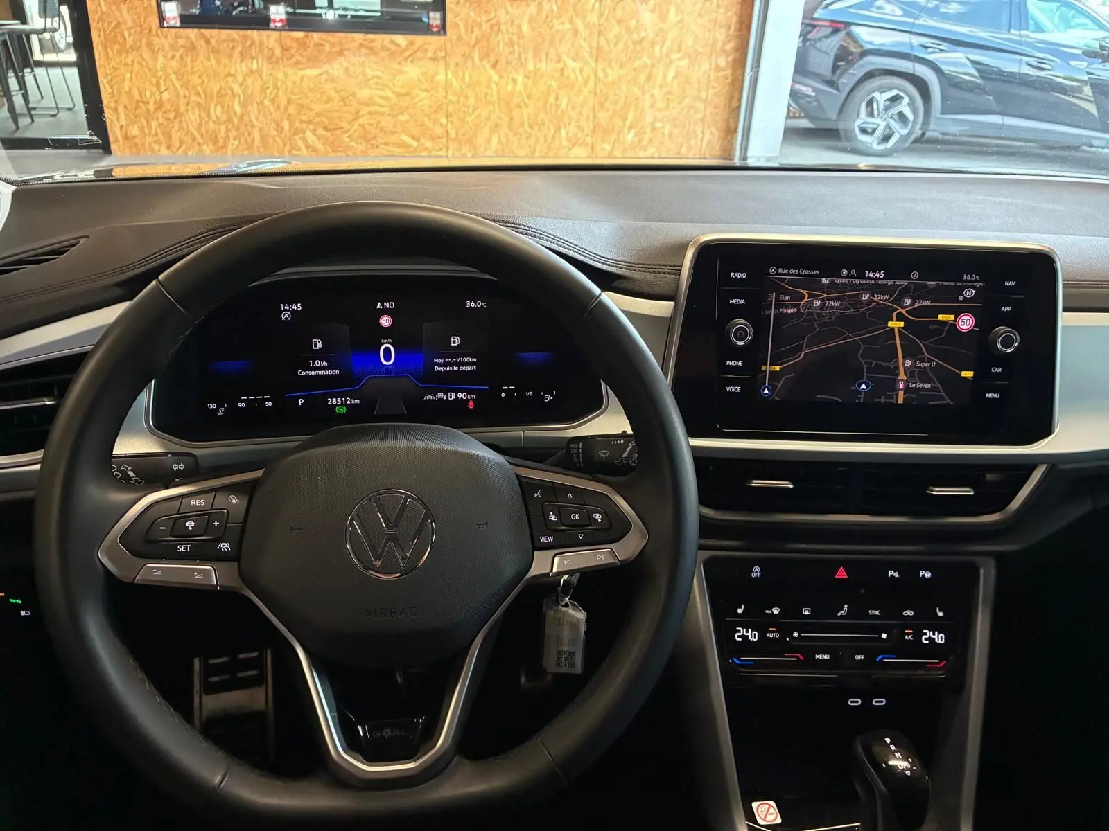 Vue intérieure centrée sur le volant noir et le tableau de bord numérique du Volkswagen T-Roc 2025 gris clair.