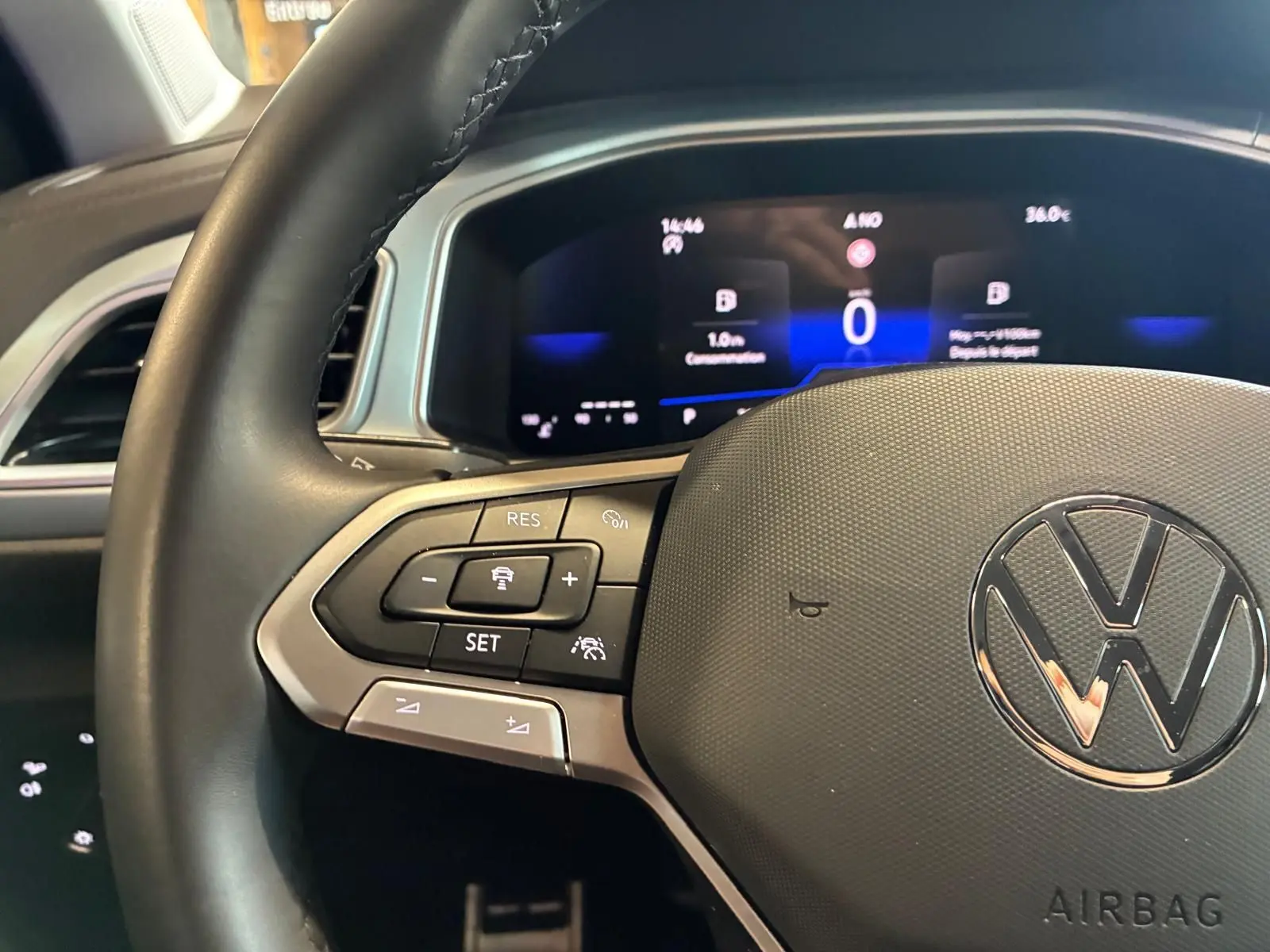 Vue rapprochée du volant noir de Volkswagen T-Roc 2025 avec commandes intégrées et tableau de bord numérique allumé.