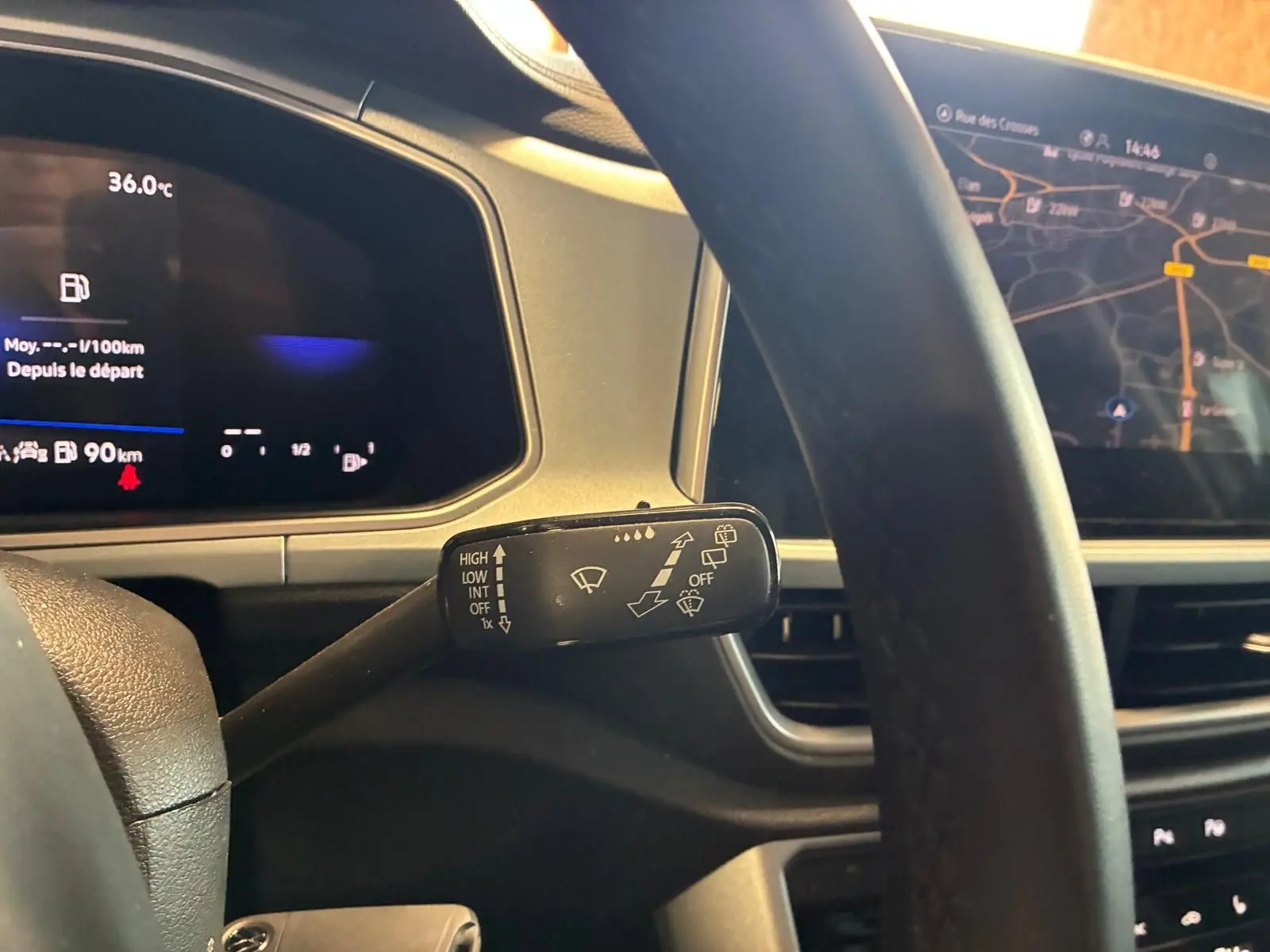 Gros plan sur le commodo d’essuie-glace du tableau de bord d’un Volkswagen T-Roc 2025 gris clair avec écran GPS visible.