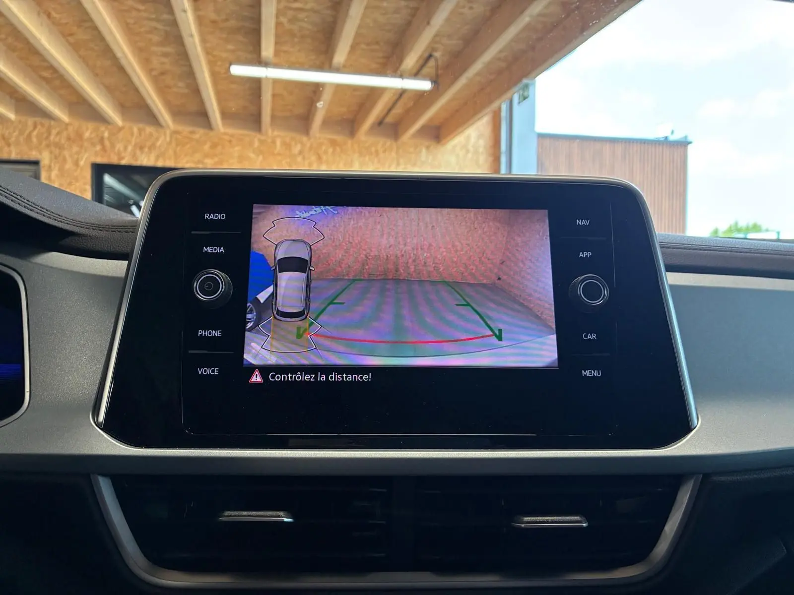 Écran central du Volkswagen T-Roc 2025 montrant la caméra de recul avec alertes de distance, intérieur noir.