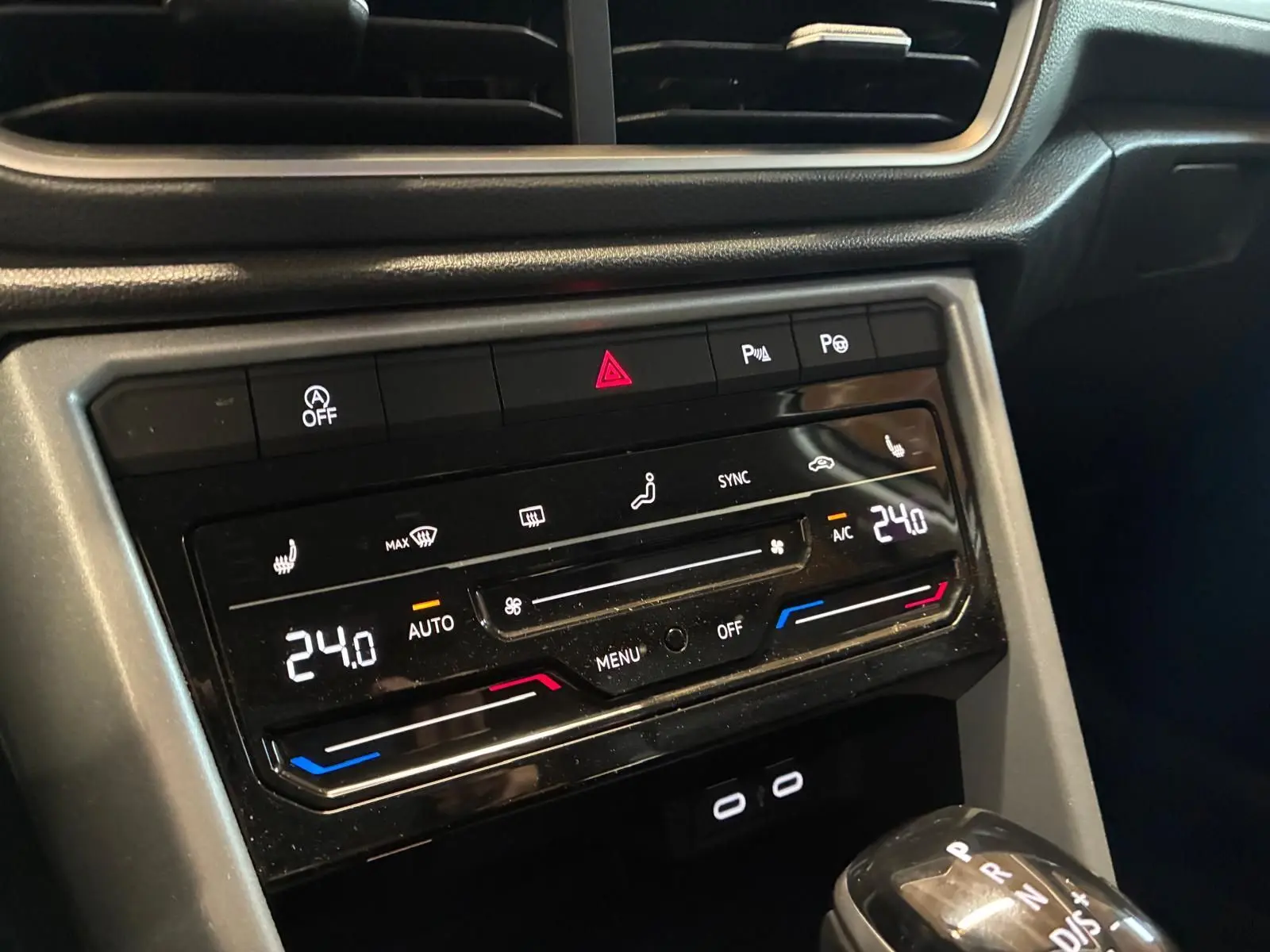 Gros plan sur la console centrale du Volkswagen T-Roc 2025 gris clair, mettant en valeur la climatisation digitale et le levier de vitesse automatique.
