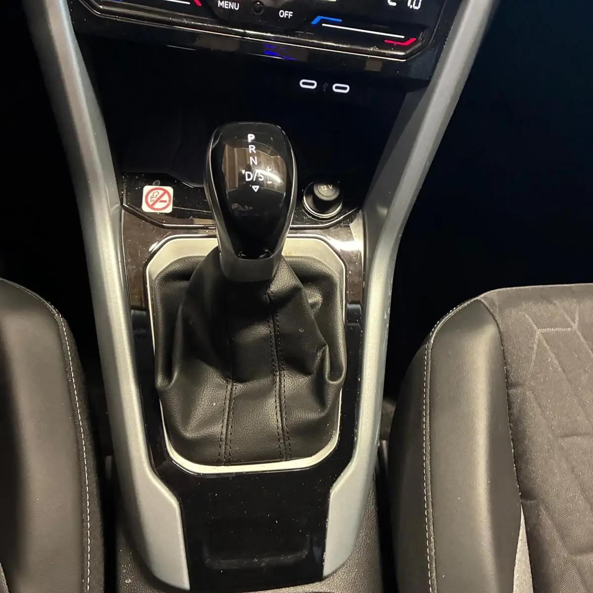 Gros plan sur la console centrale du Volkswagen T-Roc 2025, montrant le levier de vitesses automatique et la climatisation digitale.