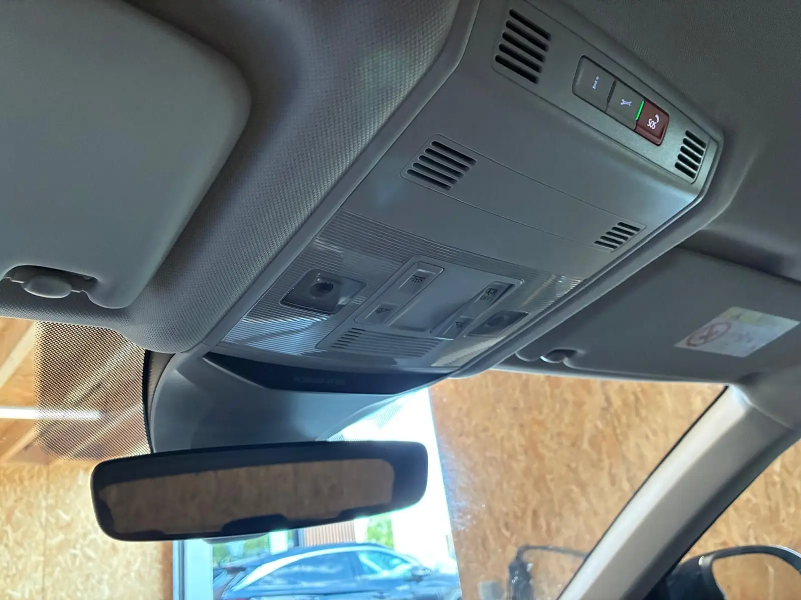 Vue intérieure du plafonnier et rétroviseur d’un Volkswagen T-Roc gris clair, avec commandes d’éclairage et toit clair.