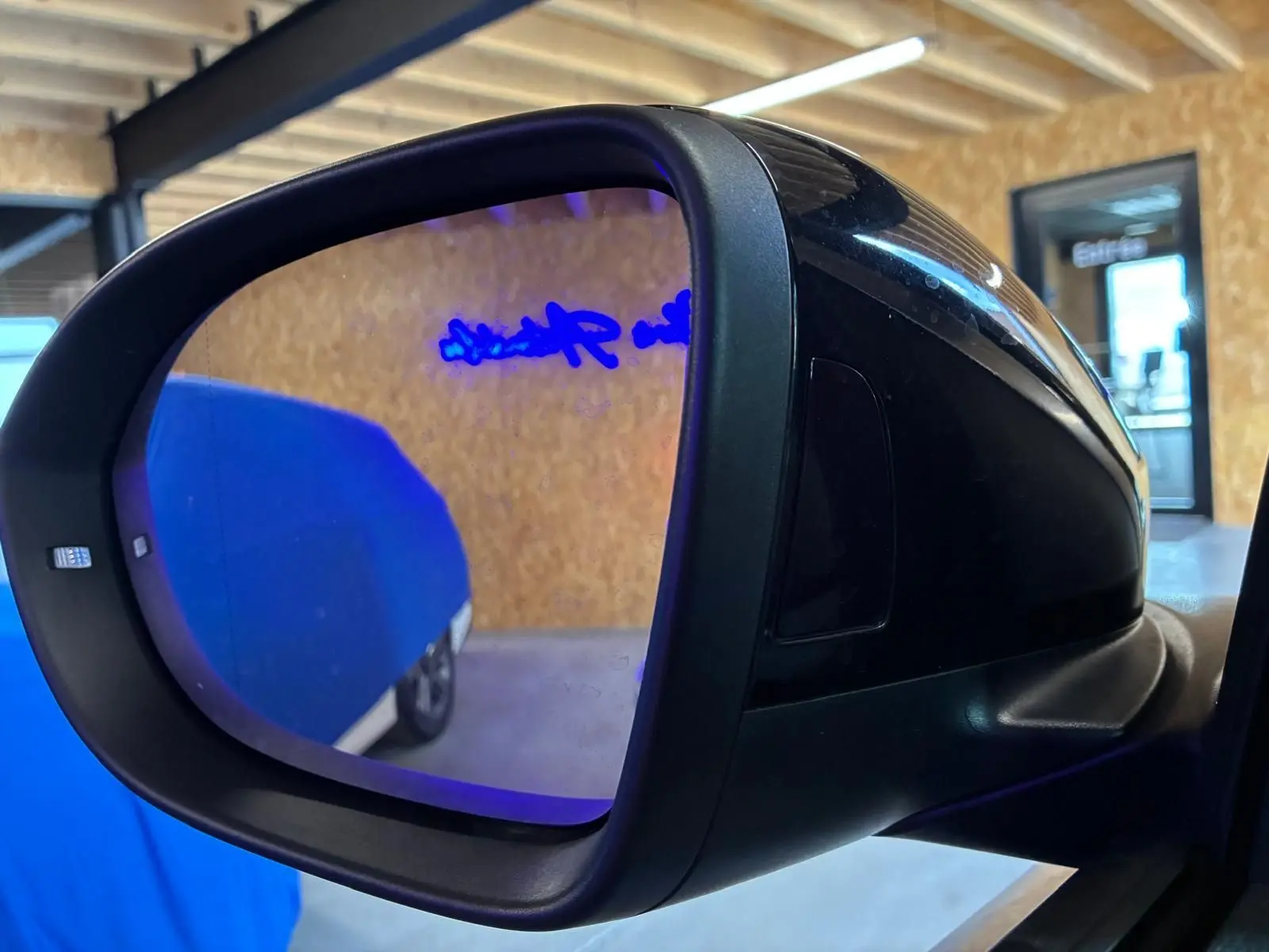 Rétroviseur extérieur côté gauche noir du Volkswagen T-Roc gris clair 2025, vue rapprochée en intérieur.