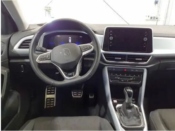 Vue intérieure du tableau de bord du Volkswagen T-Roc gris clair 2025, avec volant multifonction et écran tactile central.