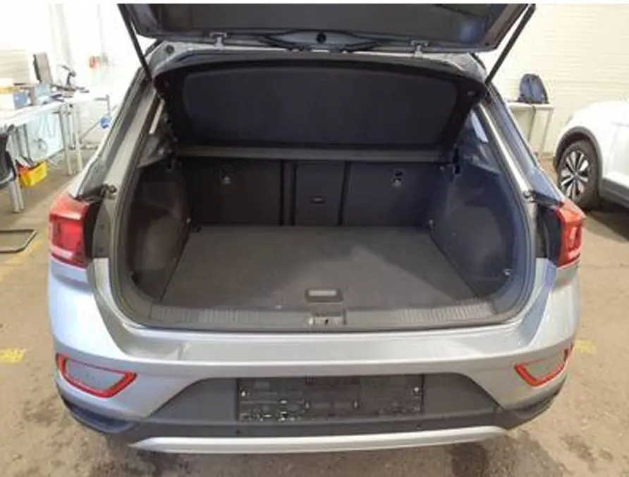 Vue arrière du coffre ouvert d'un Volkswagen T-Roc gris clair 2025, montrant l'espace de chargement vide.