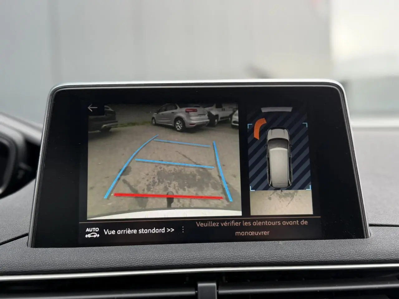 Écran tactile intérieur montrant la caméra de recul et l'affichage 360° du Peugeot 5008 bleu foncé en marche arrière.