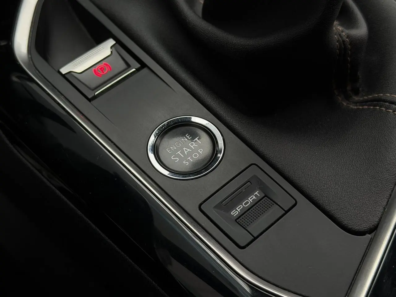 Gros plan sur la console centrale noire du Peugeot 5008 bleu foncé, avec bouton Start/Stop et mode Sport visible.
