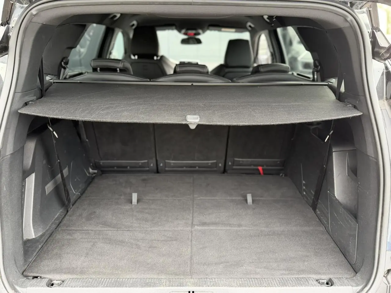 Vue arrière du coffre ouvert du Peugeot 5008 bleu foncé, montrant la plage arrière et les sièges rabattus.