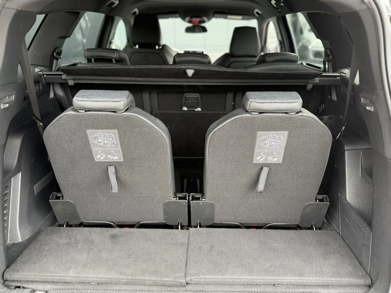 Vue arrière du coffre du Peugeot 5008 bleu foncé avec les deux sièges escamotés de la troisième rangée relevés.
