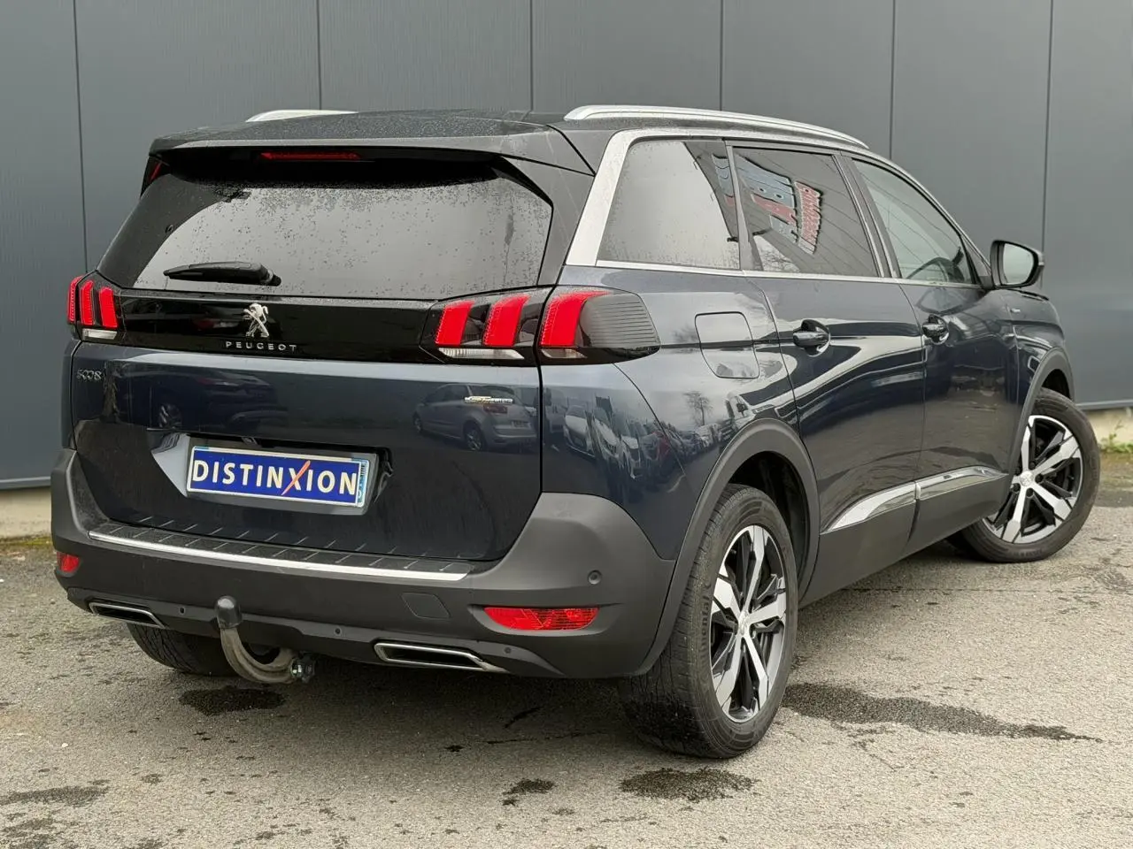 Vue 3/4 arrière droite d’un Peugeot 5008 bleu foncé avec toit noir et jantes alliage bi-ton.