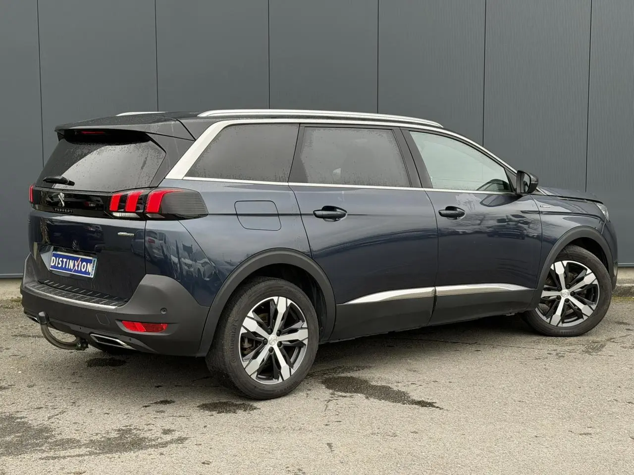 Peugeot 5008 bleu foncé vue 3/4 arrière droit, avec jantes alliage bi-ton et toit noir contrasté.
