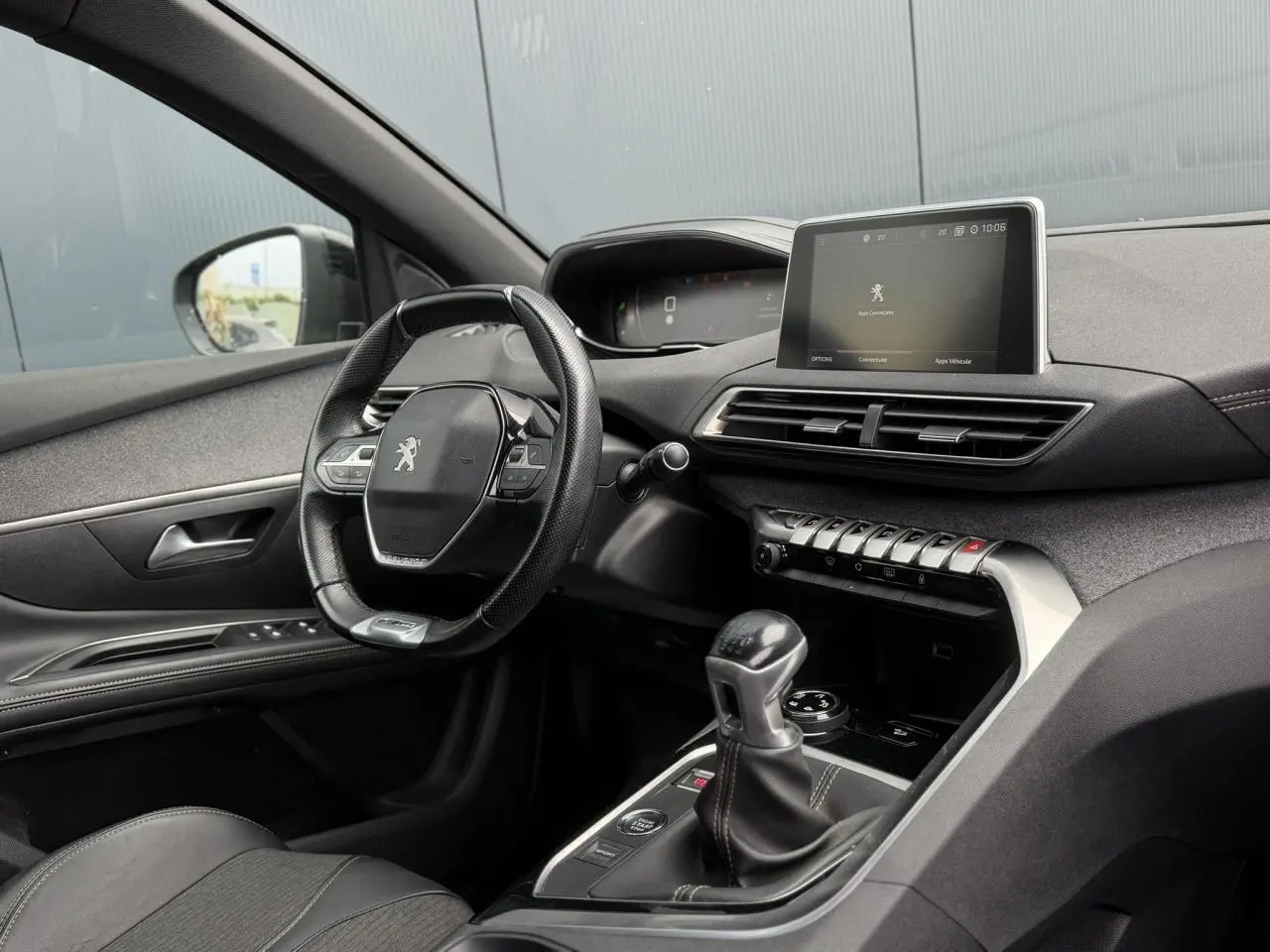 Vue intérieure côté conducteur du Peugeot 5008 bleu foncé, mettant en valeur le volant cuir GT Line et l'écran tactile central.