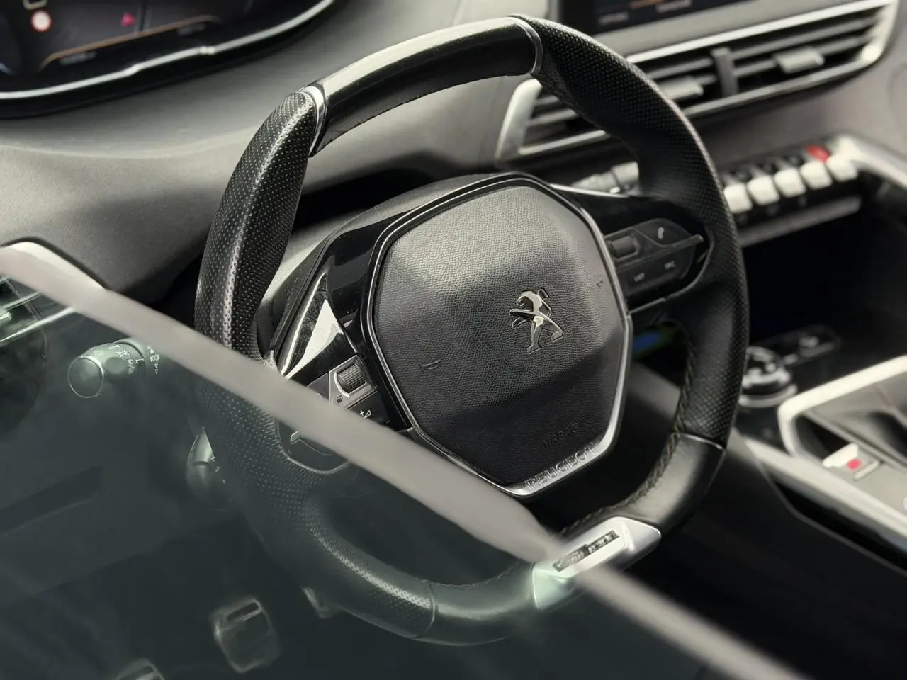 Gros plan sur le volant cuir perforé noir du Peugeot 5008 GT Line 2019 avec tableau de bord et console partiellement visibles.