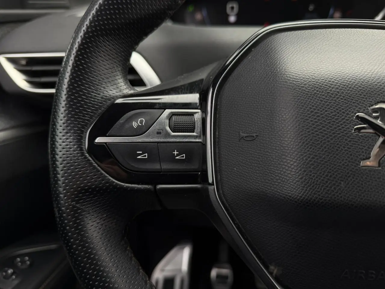Gros plan sur le volant cuir perforé noir du Peugeot 5008 GT Line avec commandes intégrées côté gauche.