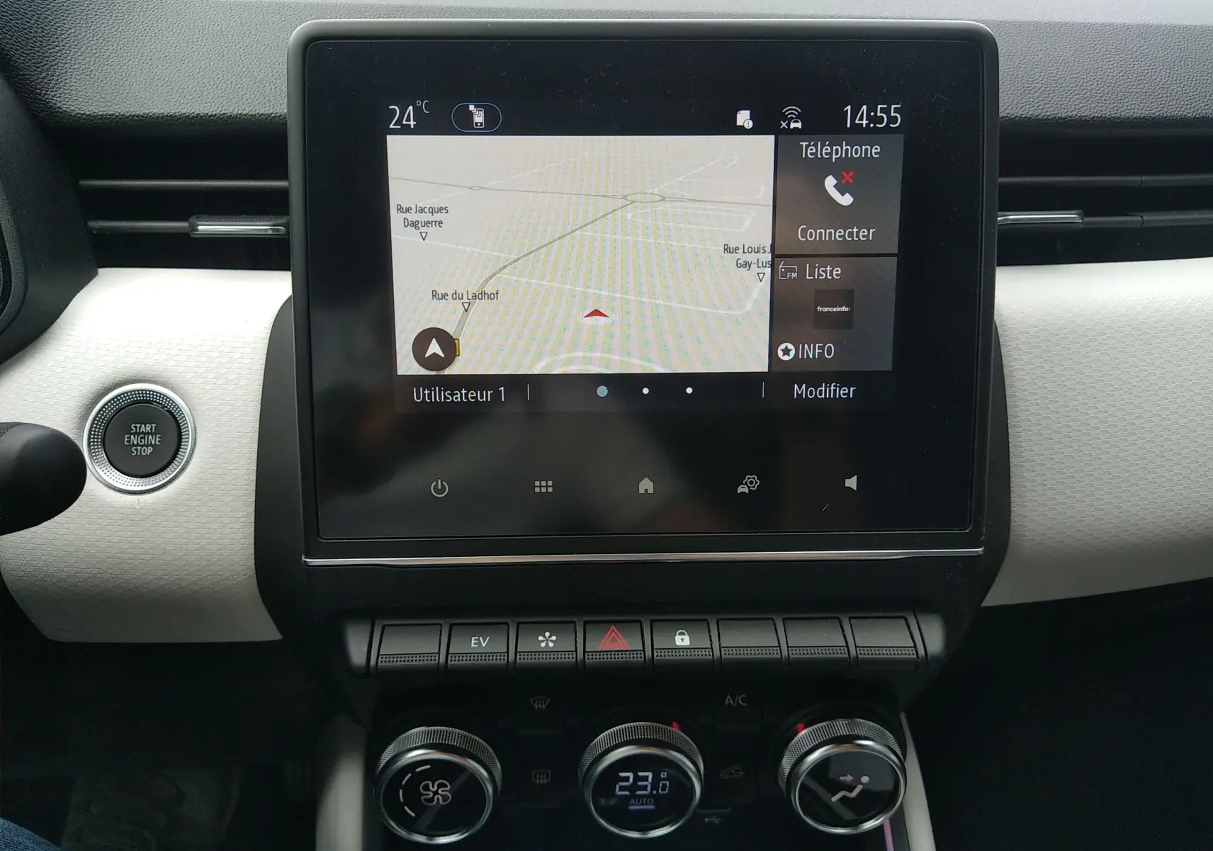 Vue rapprochée de l’écran tactile central et des commandes de climatisation de la Renault Clio V E-TECH orange, intérieur moderne.