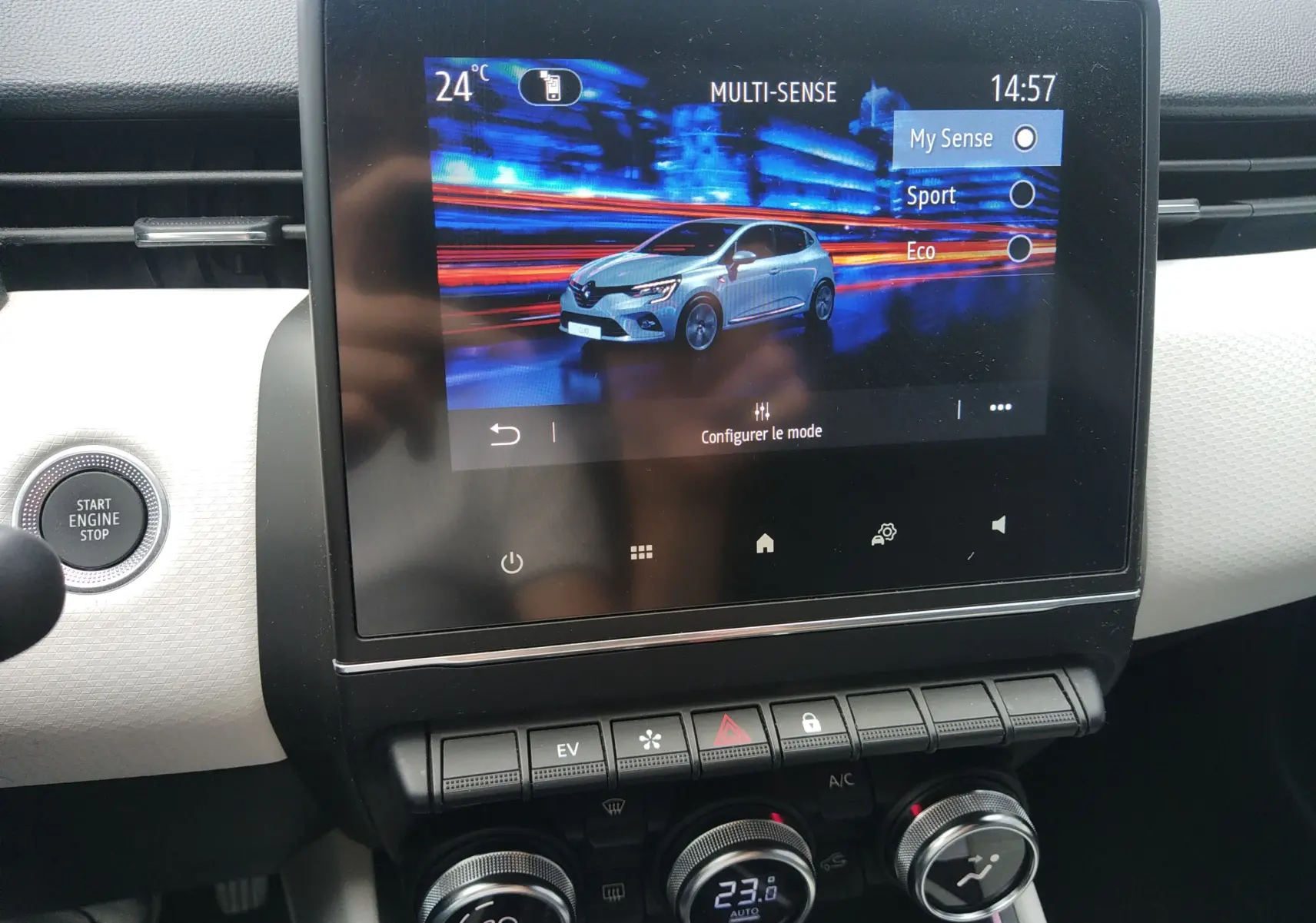 Écran tactile intérieur montrant une Renault Clio V blanche en mode Multi-Sense, avec commandes de climatisation en dessous.
