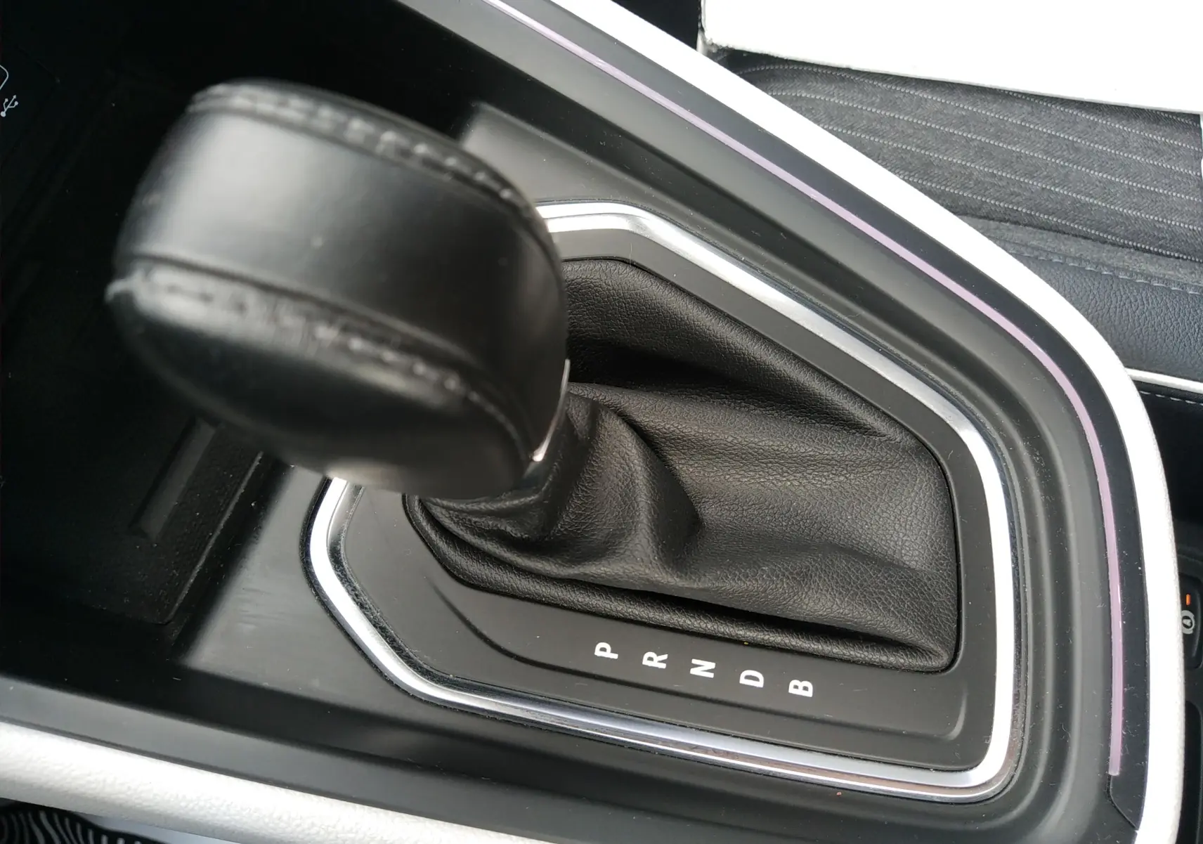 Gros plan sur le levier de vitesses automatique noir de la Renault Clio V E-TECH 140ch 21N INTENS, entouré de finitions chromées.