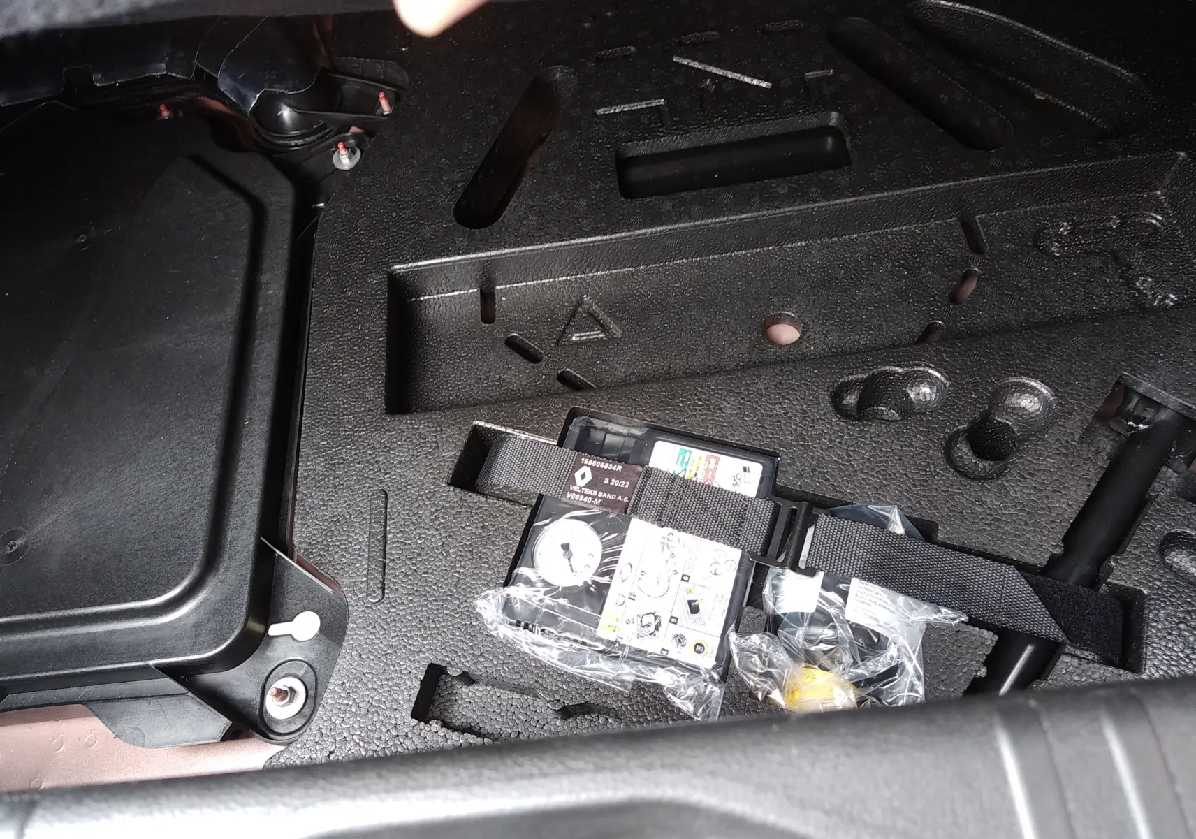 Détail du coffre de la Renault Clio V E-TECH 140ch 21N Intens 2022, montrant le kit de réparation de pneus rangé dans le compartiment.