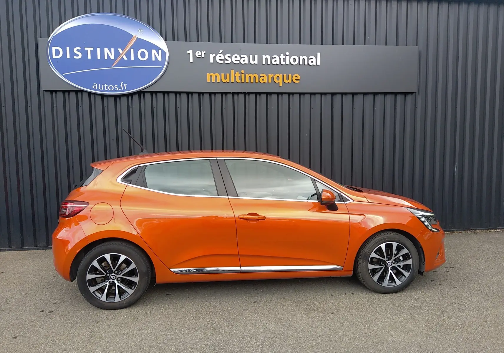 Profil droit d'une Renault Clio V E-TECH hybride orange 2022 avec jantes alliage et poignées de porte couleur carrosserie.