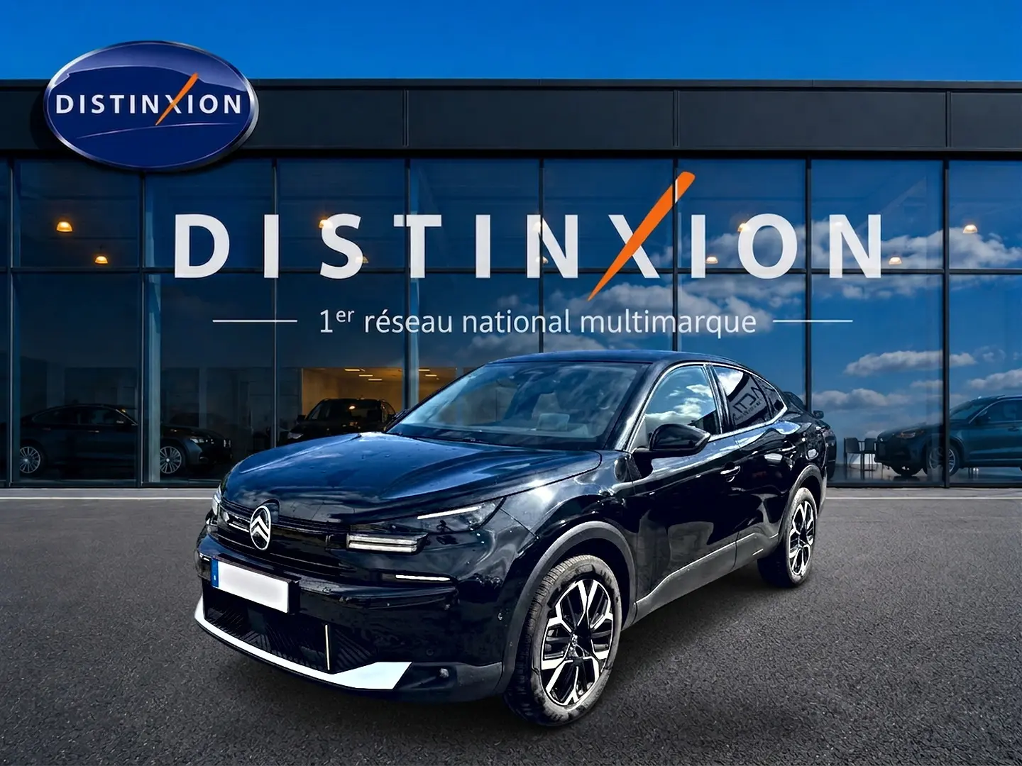 Citroën C4 X noire vue 3/4 avant droit, avec jantes alu et calandre distinctive devant showroom Distinxion.