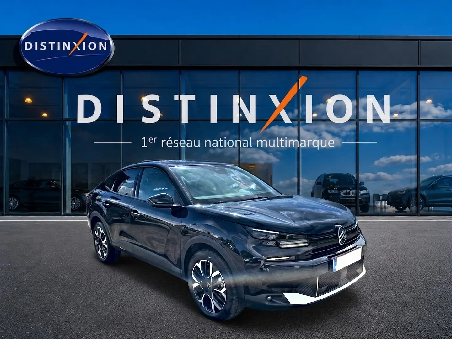 Citroën C4 X noire vue 3/4 avant droit, avec jantes alu et calandre distinctive devant showroom Distinxion.