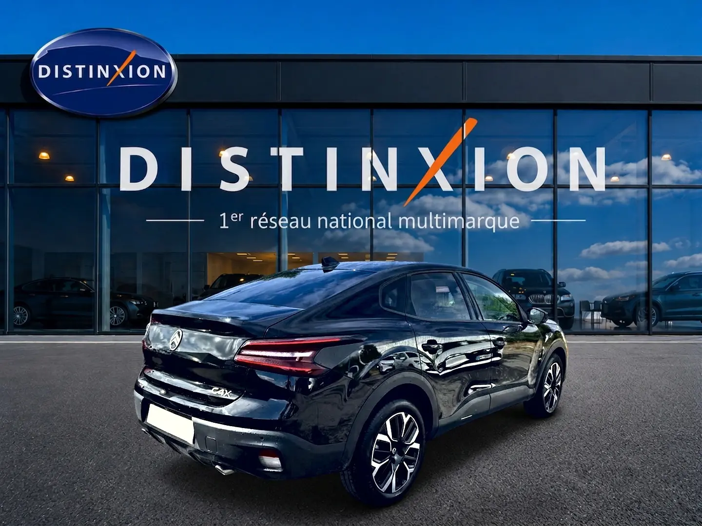 Vue 3/4 arrière droite d'une Citroën C4 X noire brillante, avec feux arrière LED et jantes alu distinctives.