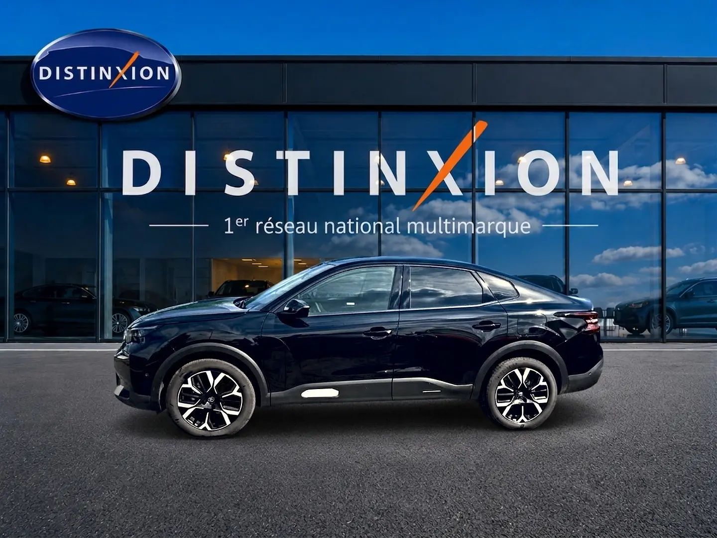 Vue de profil côté gauche d'une Citroën C4 X noire 2025 avec jantes alu et lignes fluides devant une vitrine Distinxion.