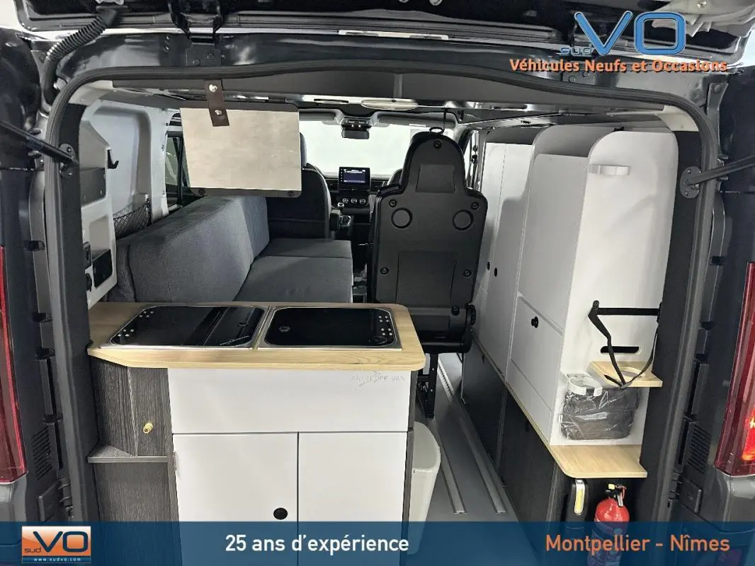 Vue arrière intérieure du Renault Trafic Fourgon gris 2025 aménagé avec kitchenette et banquette grise.