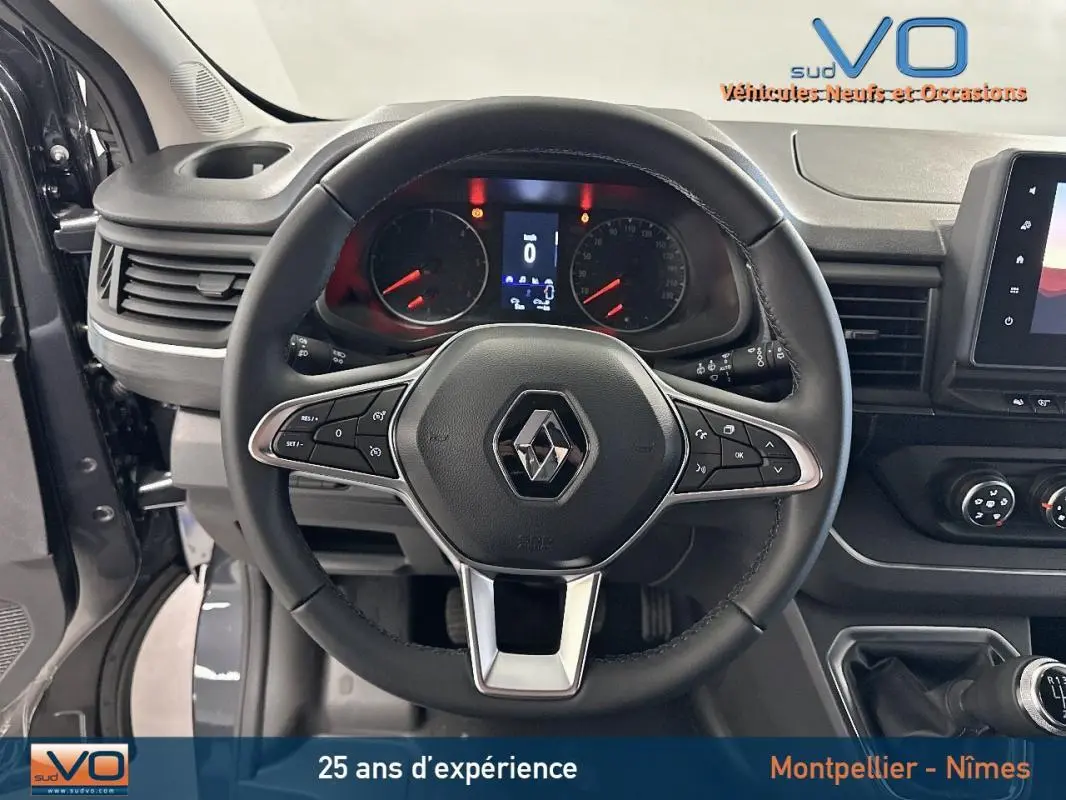 Vue intérieure centrée sur le volant noir du Renault Trafic Fourgon gris avec tableau de bord et commandes visibles