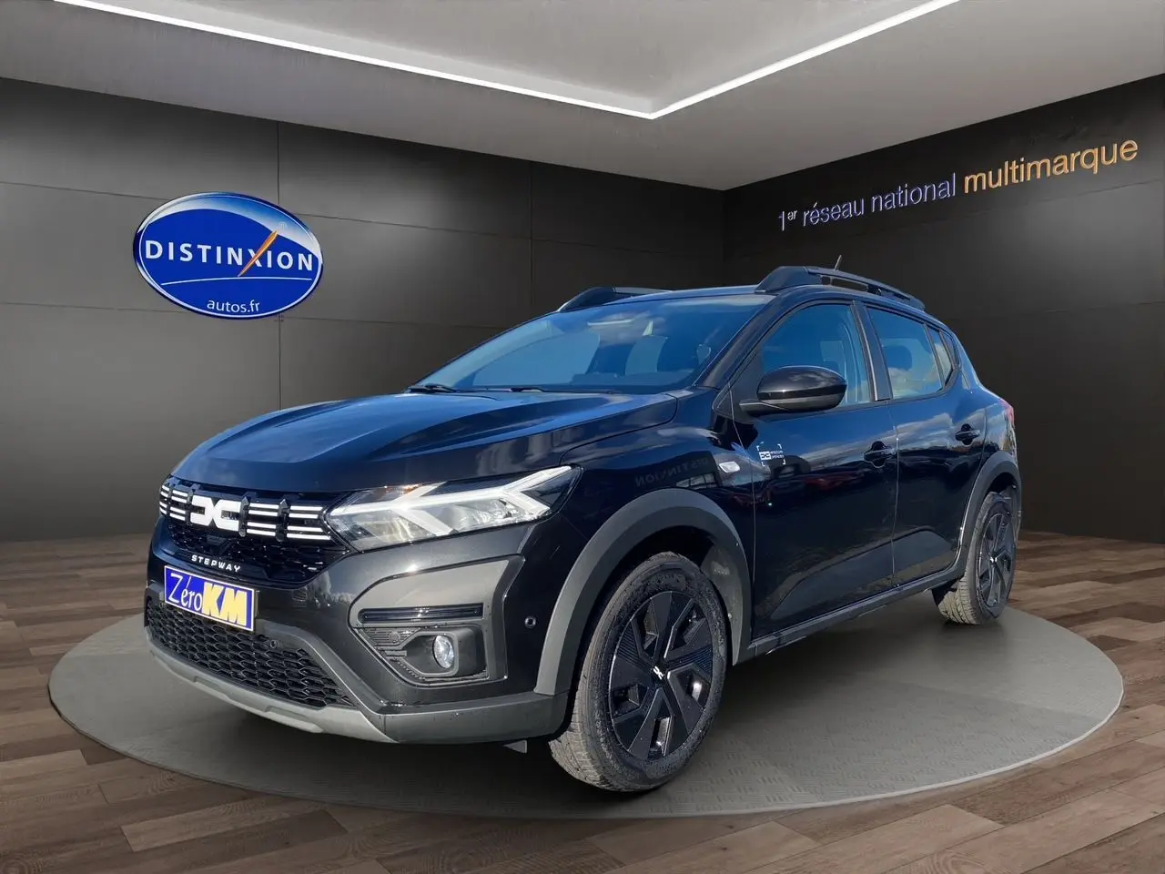 Dacia Sandero Stepway noir en 3/4 avant droit, avec barres de toit et jantes noires distinctives.