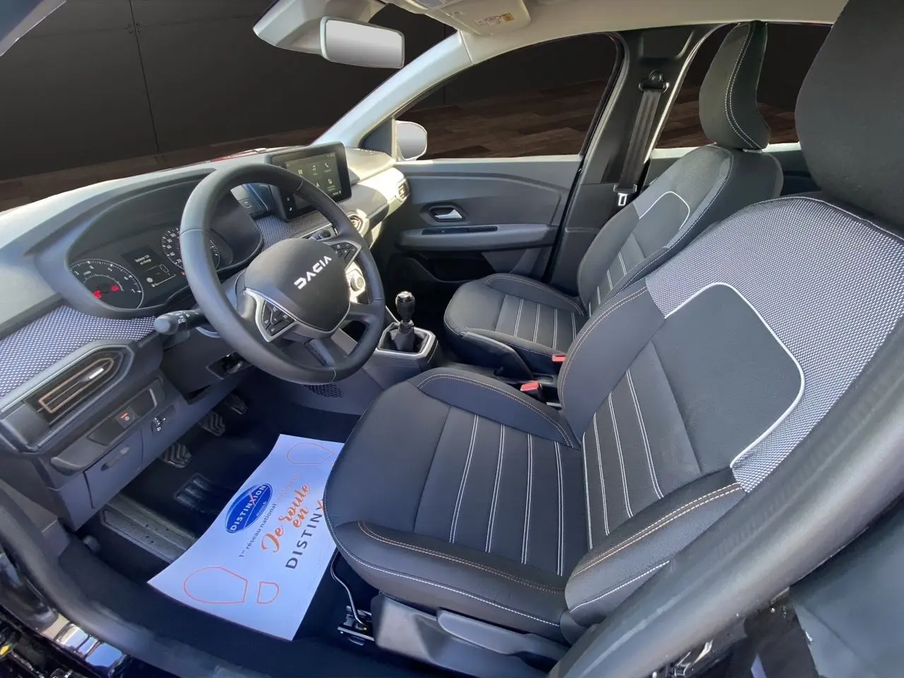 Vue intérieure côté conducteur de la Dacia Sandero Stepway 2025 avec sièges tissu noir et tableau de bord moderne.
