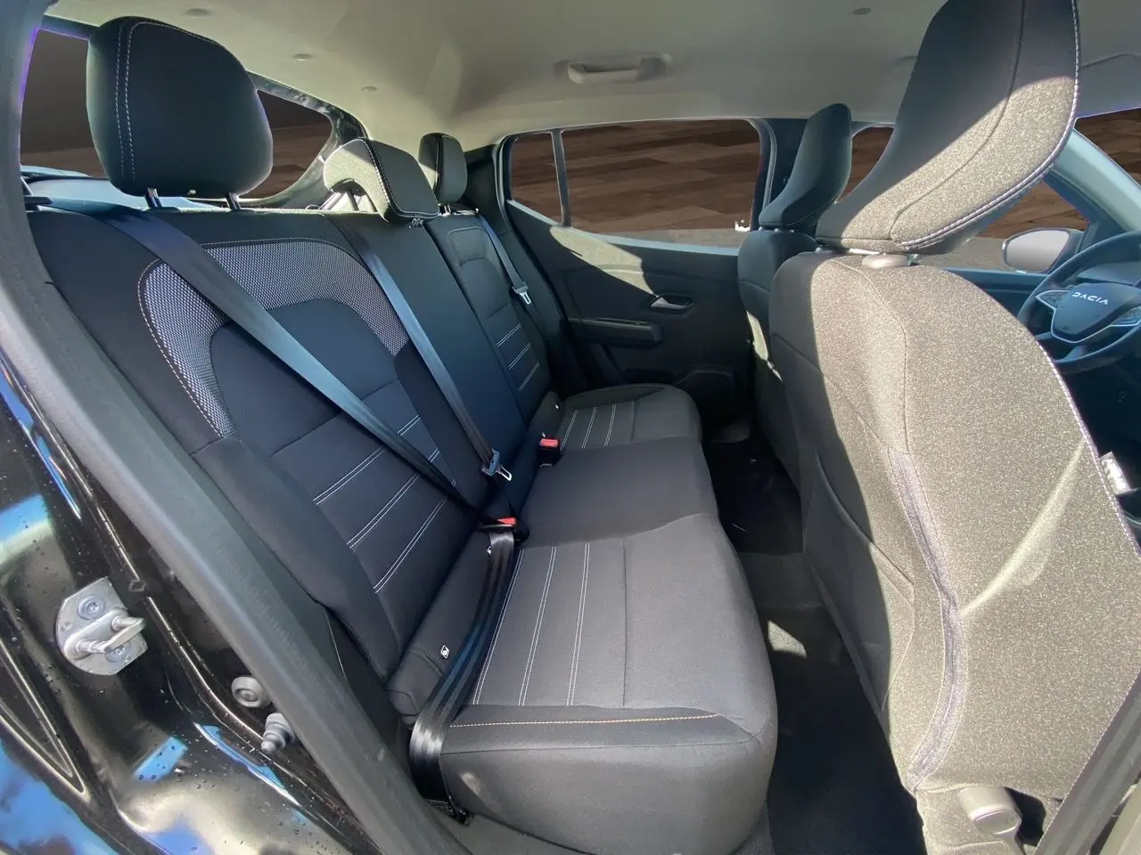 Vue intérieure côté droit des sièges arrière noirs en tissu de la Dacia Sandero Stepway 2025 avec ceinture de sécurité attachée.