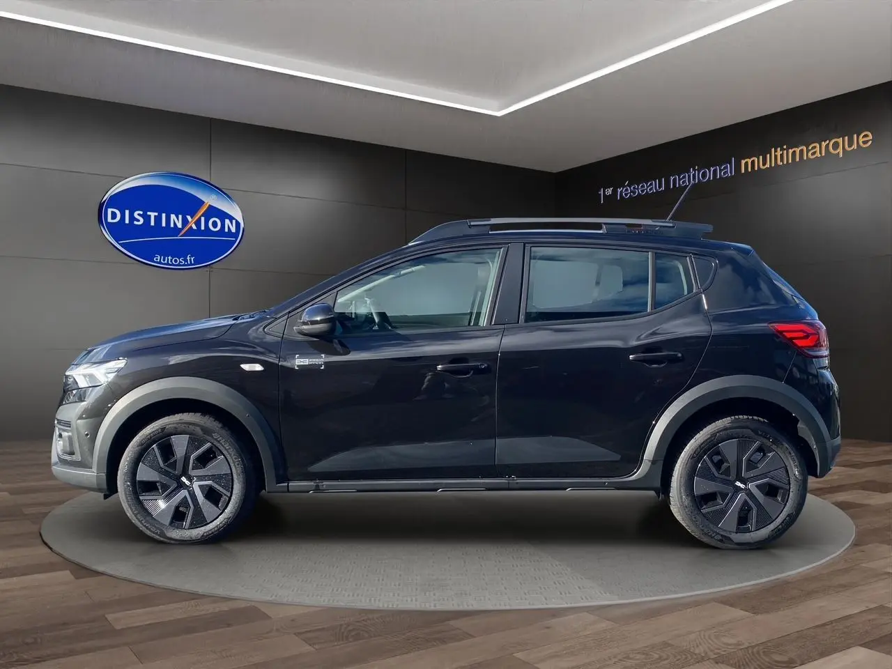 Profil côté gauche d'une Dacia Sandero Stepway noire 2025 avec jantes modernes et barres de toit visibles.