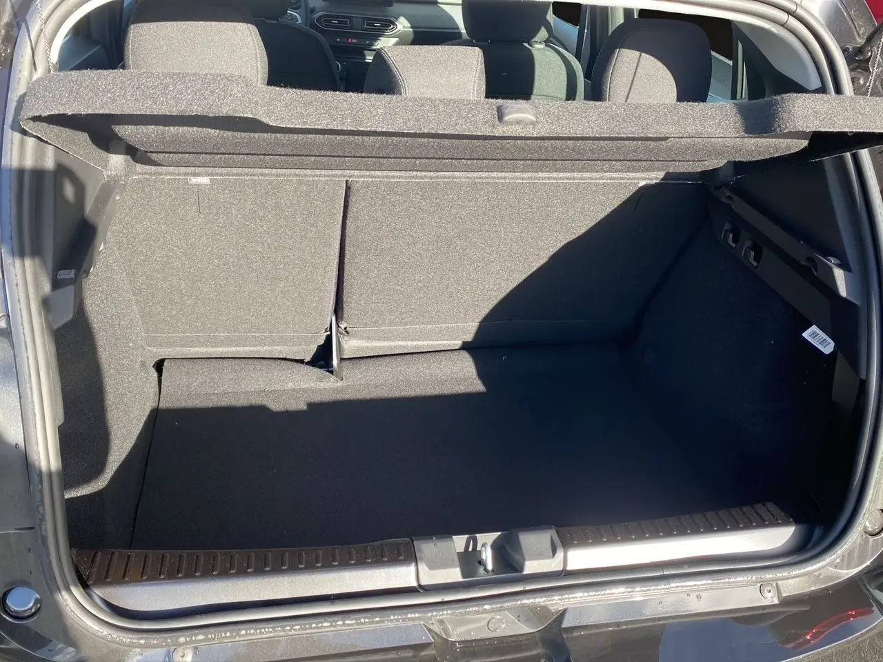 Coffre ouvert vu de l'arrière d'une Dacia Sandero Stepway noire, montrant l'espace de chargement et la banquette arrière.
