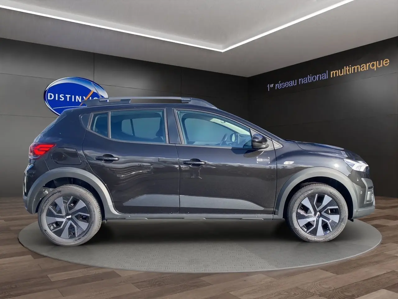 Profil côté gauche d'une Dacia Sandero Stepway noire 2025 avec barres de toit et jantes alliage distinctives.