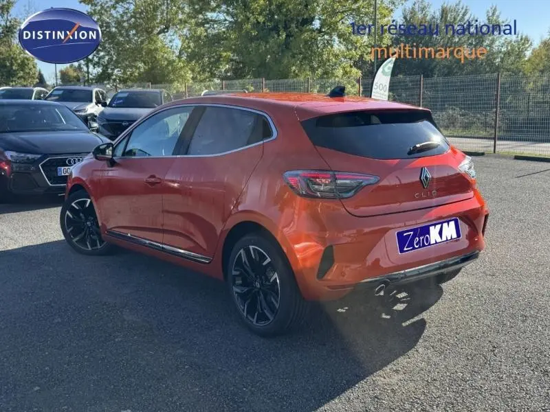 Vue 3/4 arrière droite d'une Renault Clio orange Valencia 2025 avec jantes alliage noires et vitres teintées.