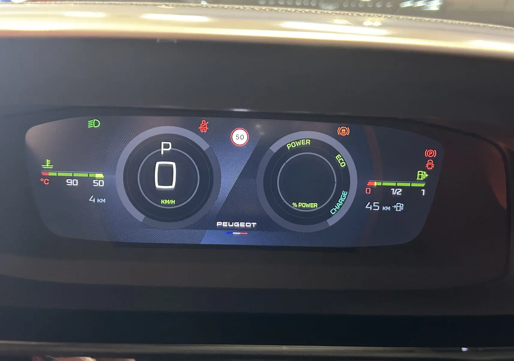 Tableau de bord numérique 3D de Peugeot 308 Hybrid blanc, affichant vitesse, charge et température moteur.
