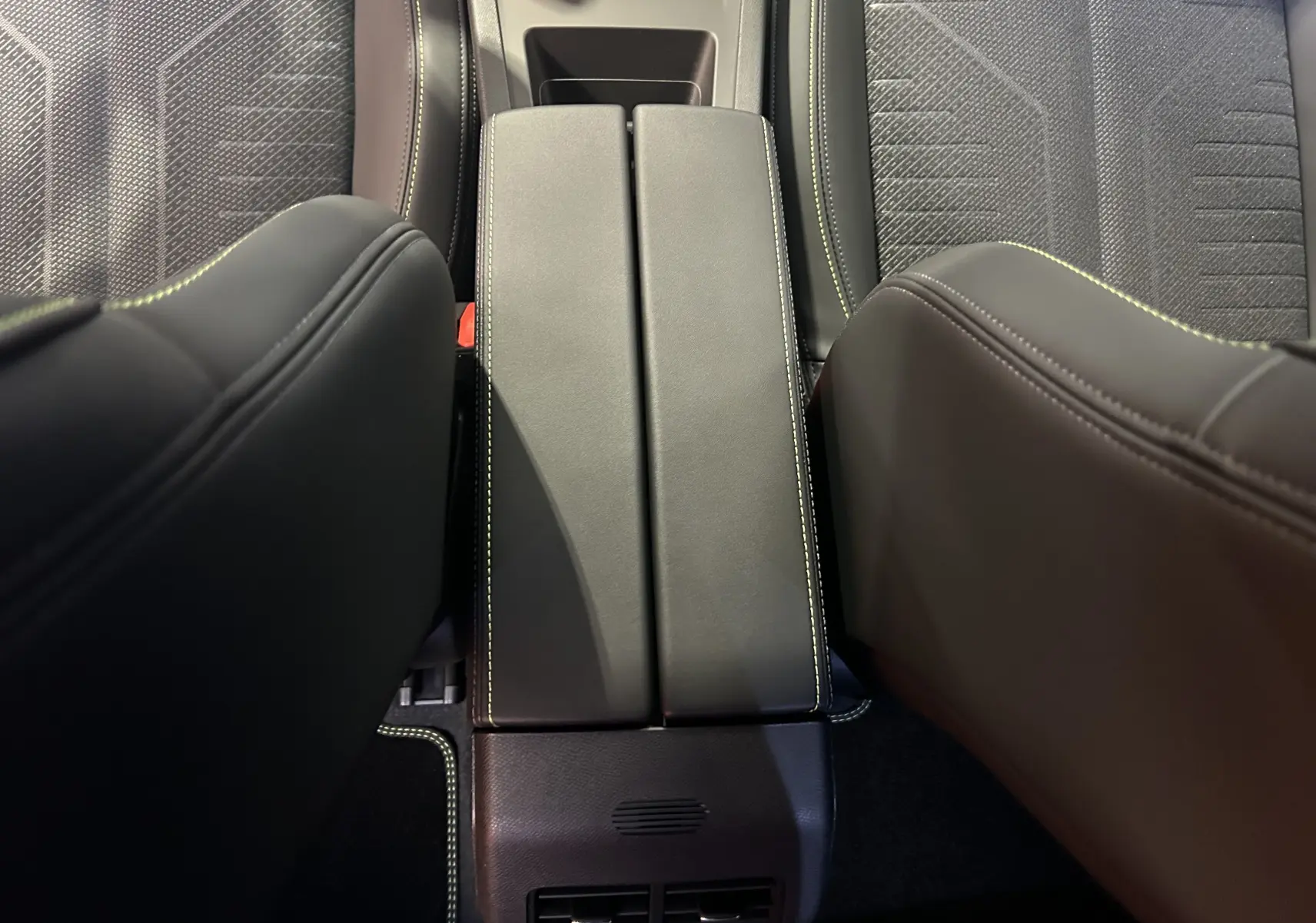 Vue plongeante sur la console centrale noire et les sièges en cuir noir avec surpiqûres contrastantes du Peugeot 308 HYBRID 2026.