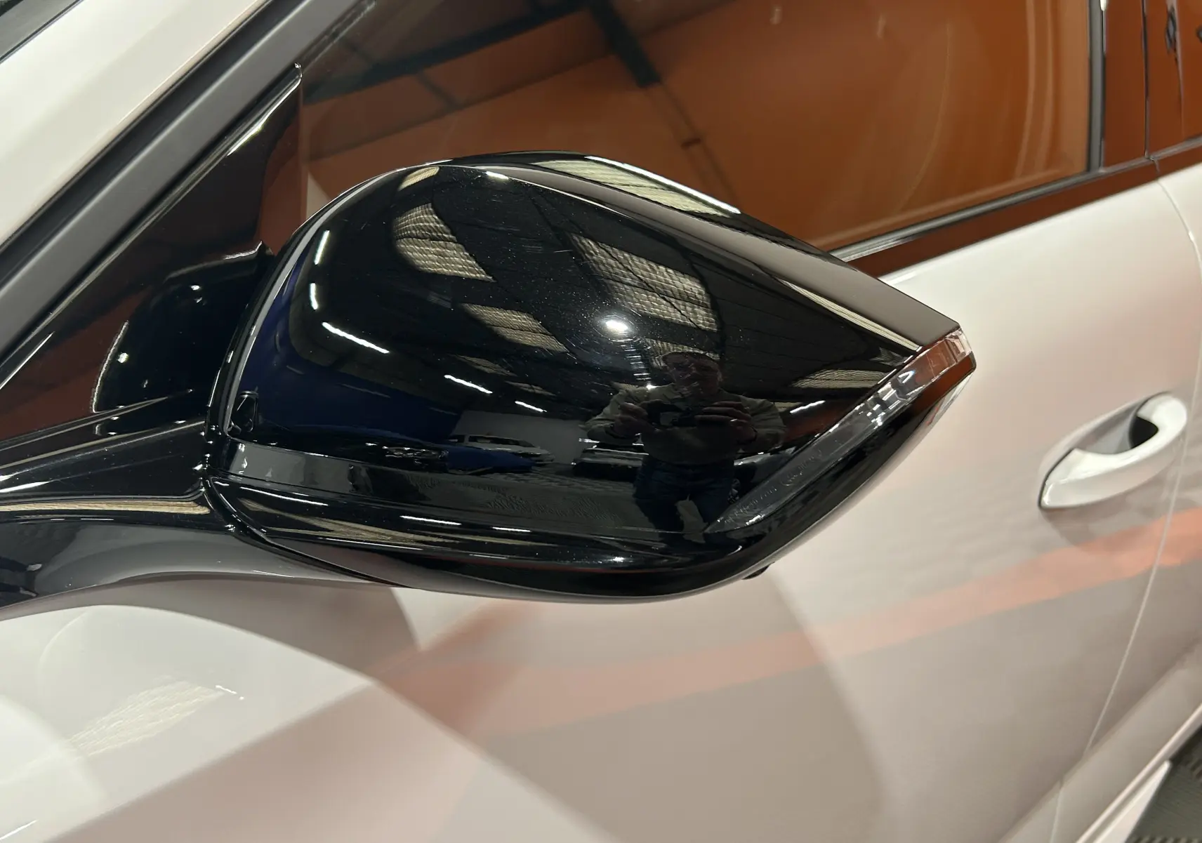 Gros plan sur le rétroviseur noir brillant côté gauche d'une Peugeot 308 blanche Okenite, avec reflet intérieur visible.
