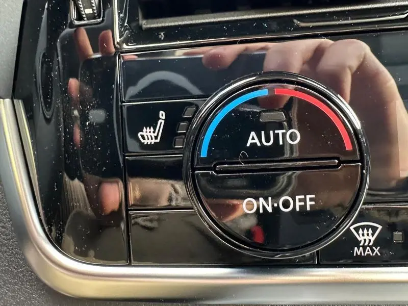 Gros plan sur le bouton de réglage automatique de la climatisation avec fonction siège chauffant du Nissan Qashqai Hybrid e-POWER noir.