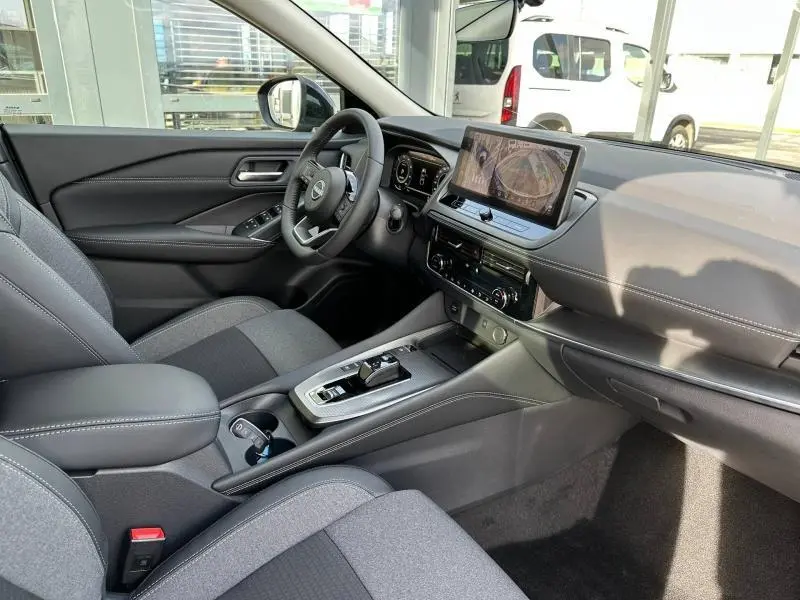 Vue intérieure côté conducteur du Nissan Qashqai Hybrid e-POWER 2025, avec tableau de bord moderne et écran tactile central.